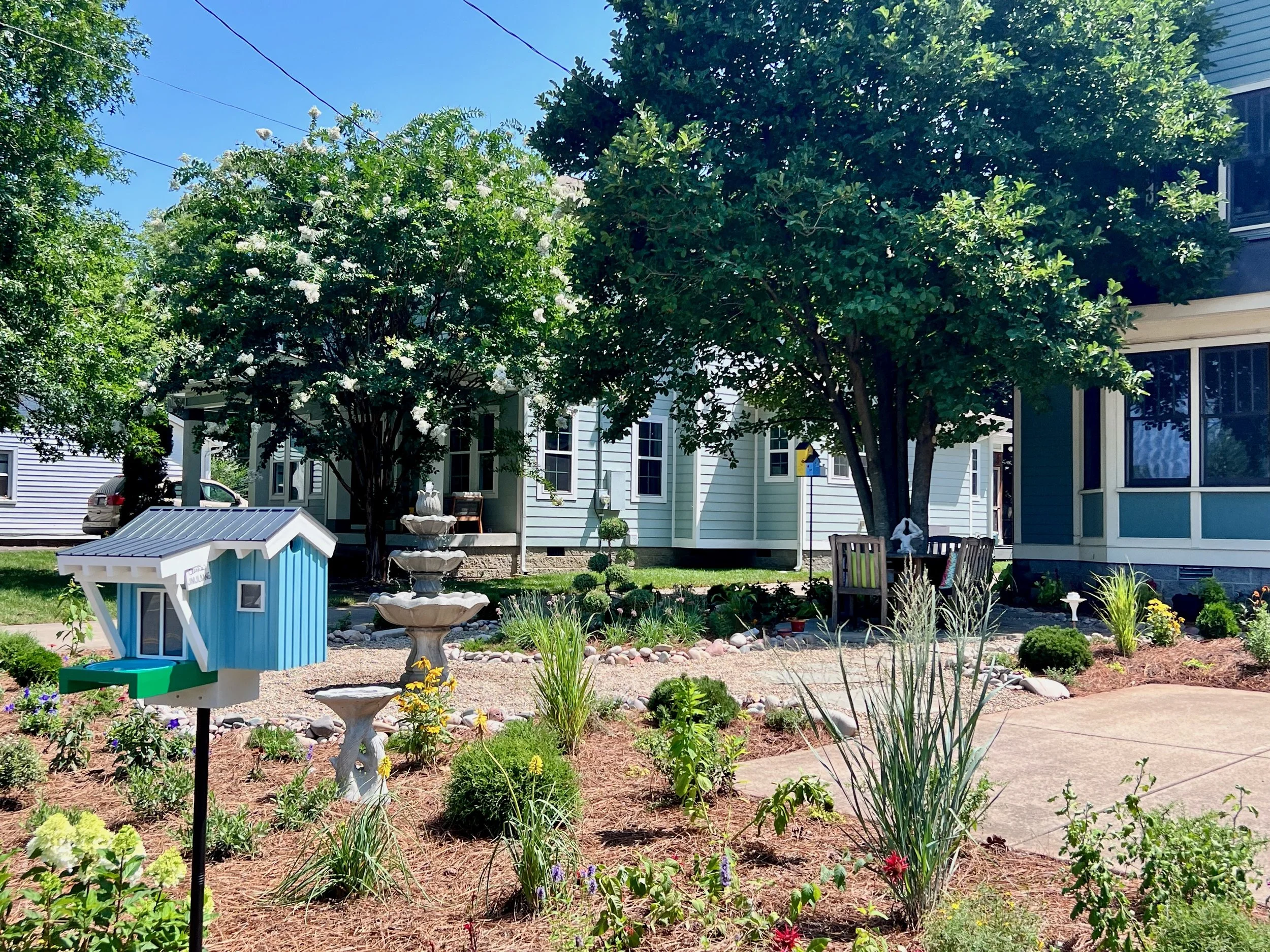 A lawnless front yard with a native perennial garde, water, feature, amd outdoor dining table designed by The Grass Girl in Sylvan Park, Nashville.