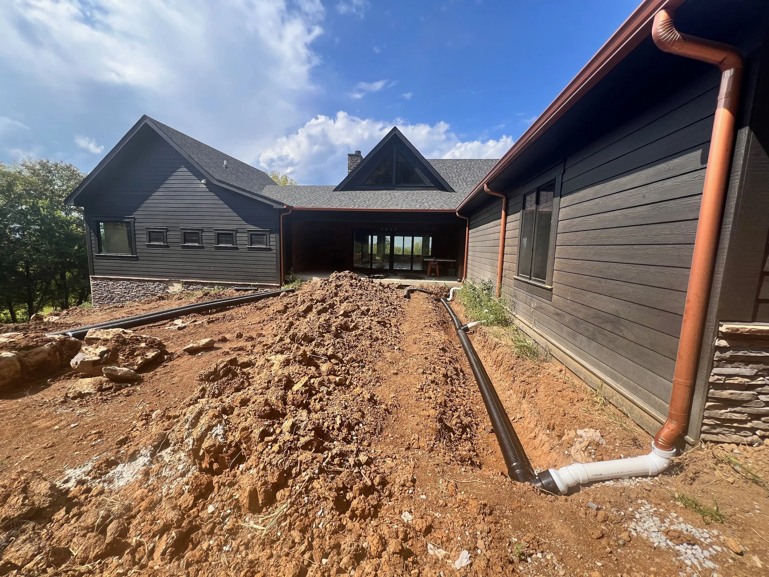 A Nashville french drainage system installed around a black Middle TN home with copper downspouts.
