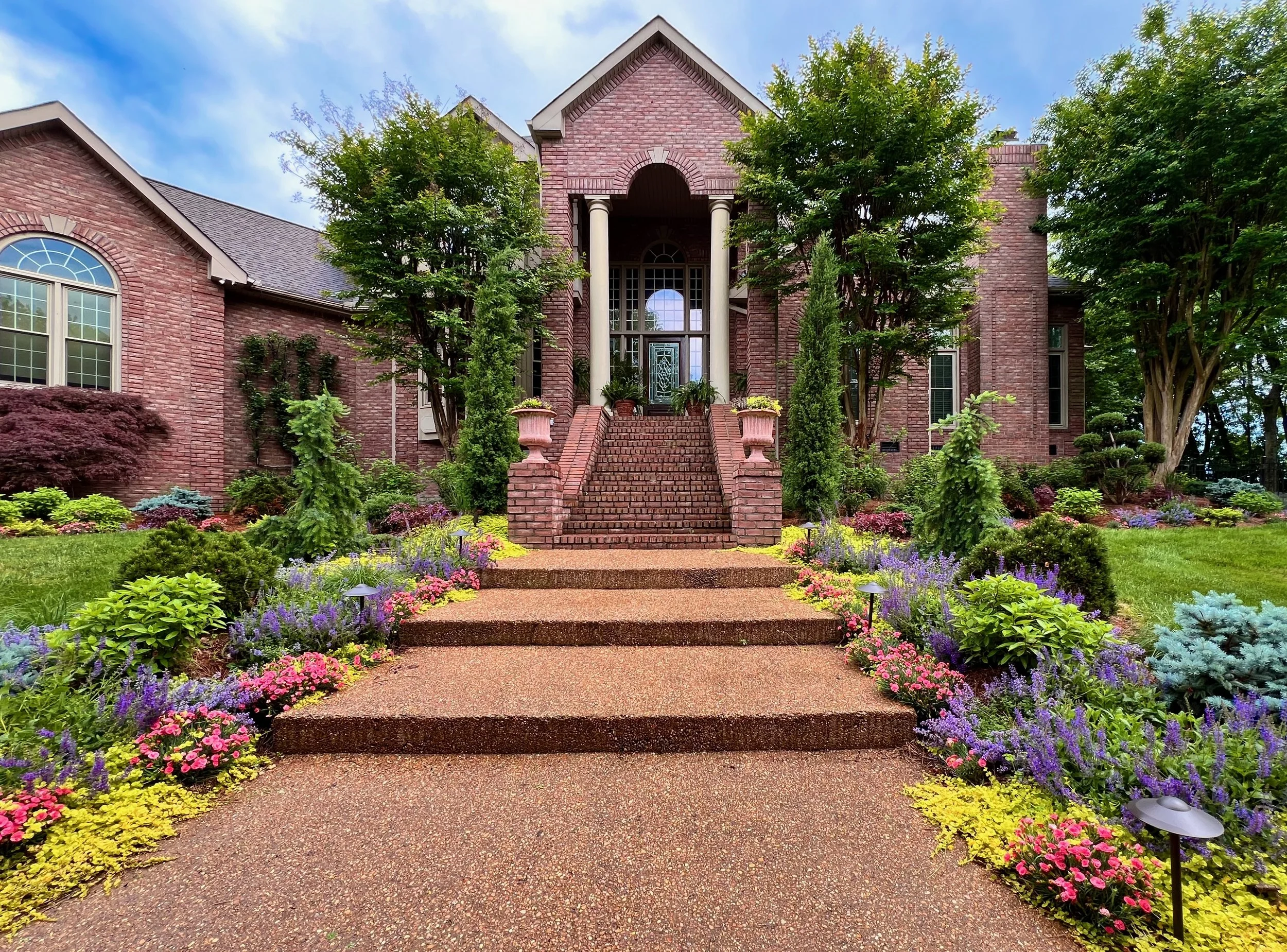 Whole property garden commission by The Grass Girl, Nashville Tennessee — layered perennial planting, fastigiate evergreens, and full arrival sequence in bloom at brick estate home.