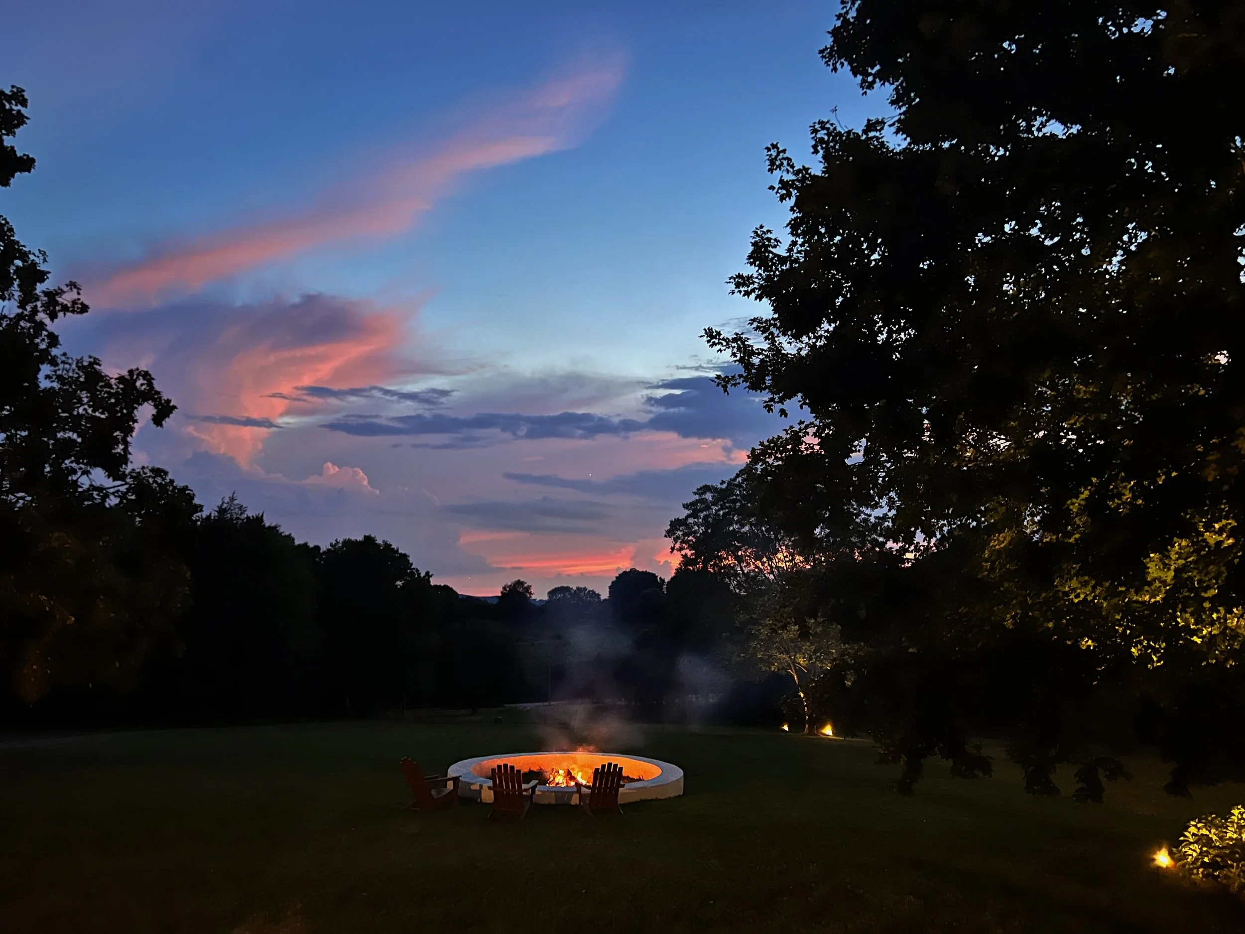 Fire pit at dusk on Clare Horne's working farm in Smith County, Tennessee — Inhabitation Design places gathering spaces where the evening light actually lands.