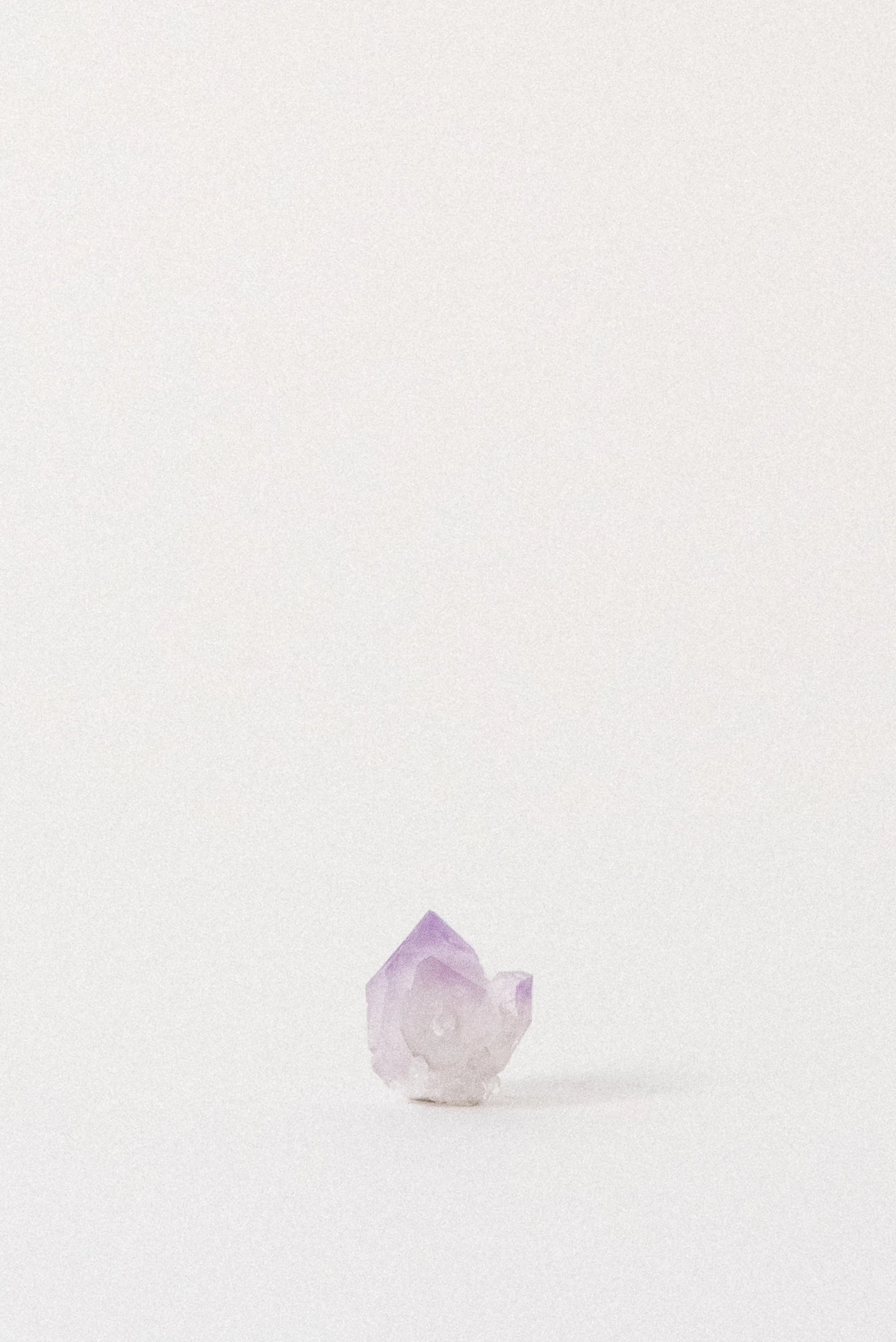 Small natural amethyst crystal with clear-to-violet color zoning, photographed on a minimal white background; sourced from Jackson’s Crossroads, Georgia