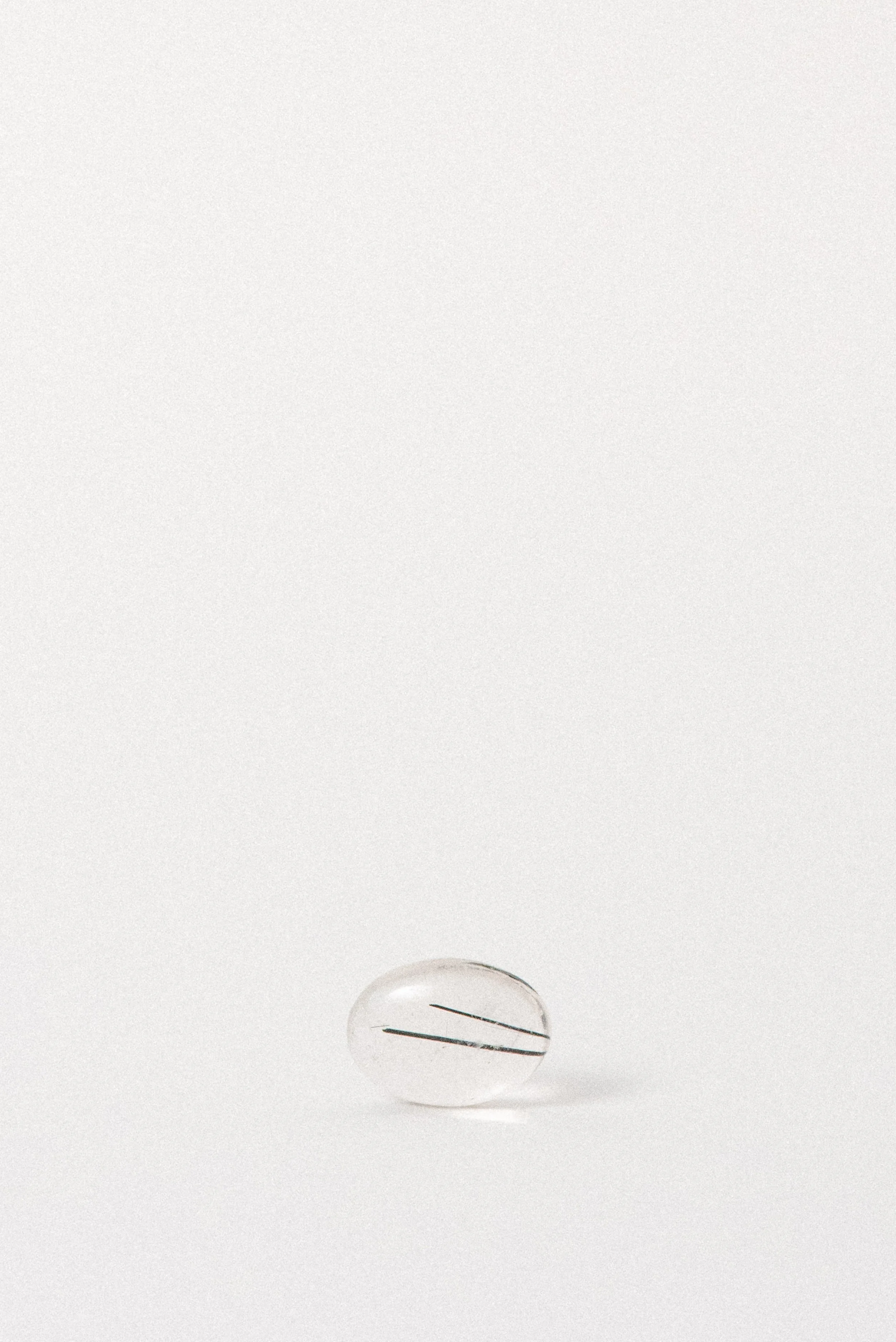 Side angle of Brazilian quartz cabochon featuring slender black tourmaline strands.