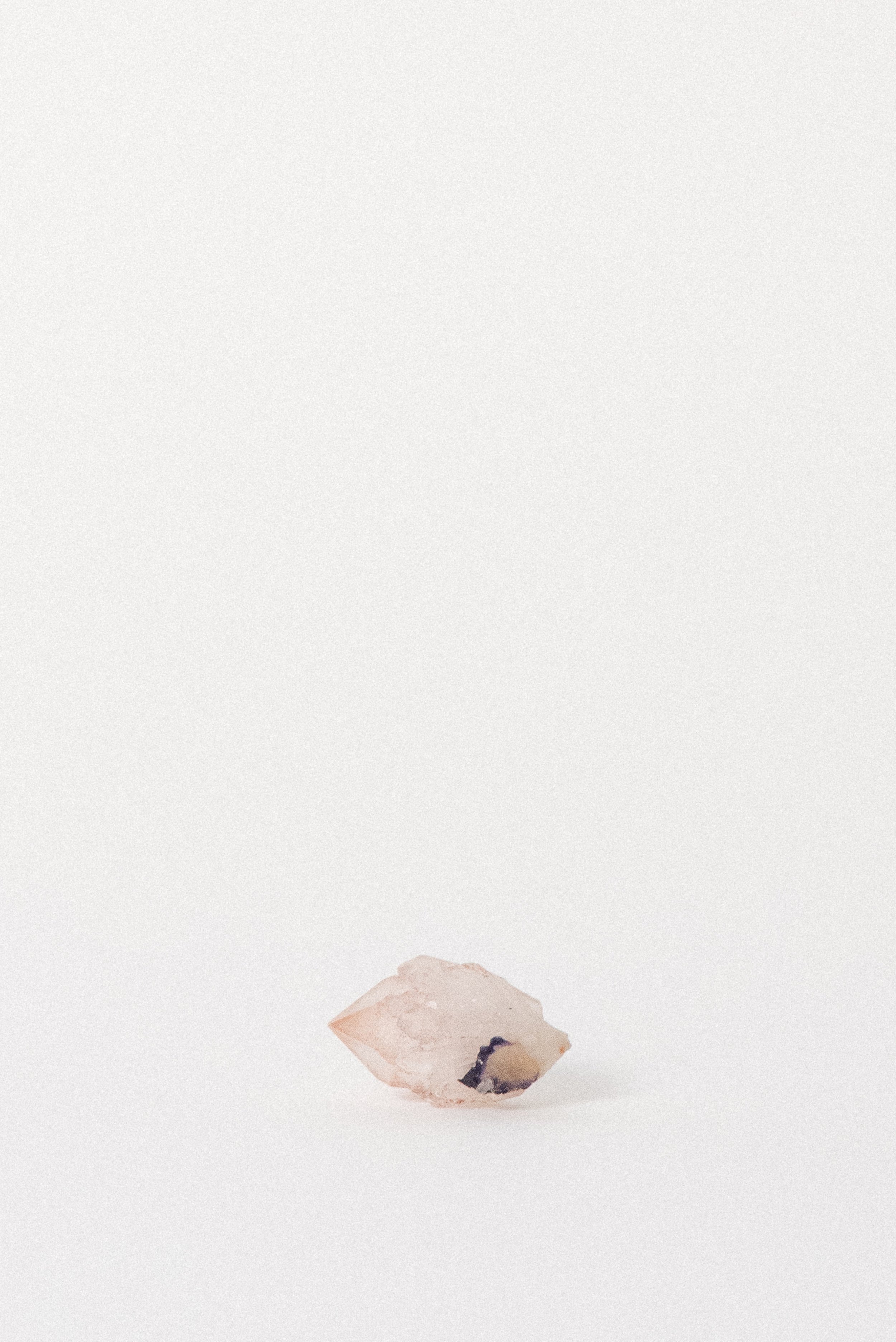 Front view of Pink Quartz with hematite and violet fluorite inclusion visible near base