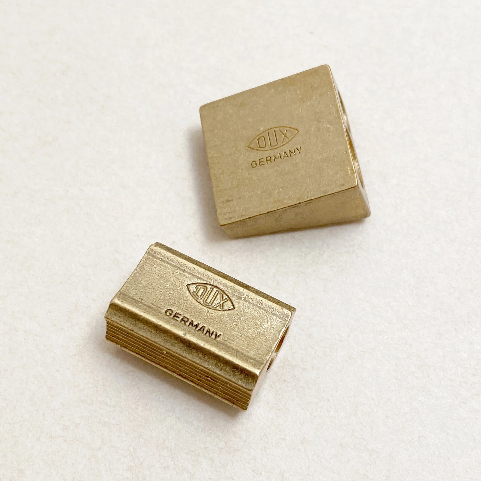 Close-up of DUX Germany engraving on brass pencil sharpeners, vintage design detail