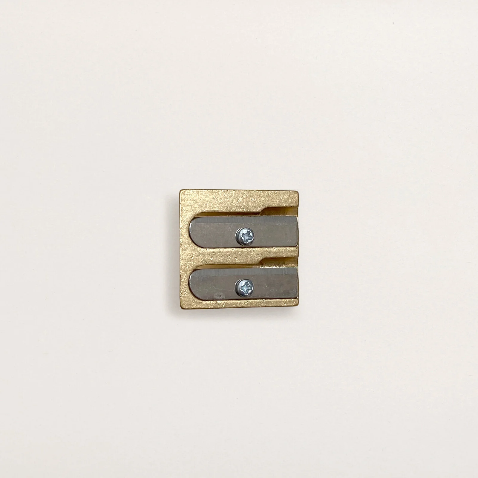 Double wedge DUX brass pencil sharpener from Germany, top view on neutral background