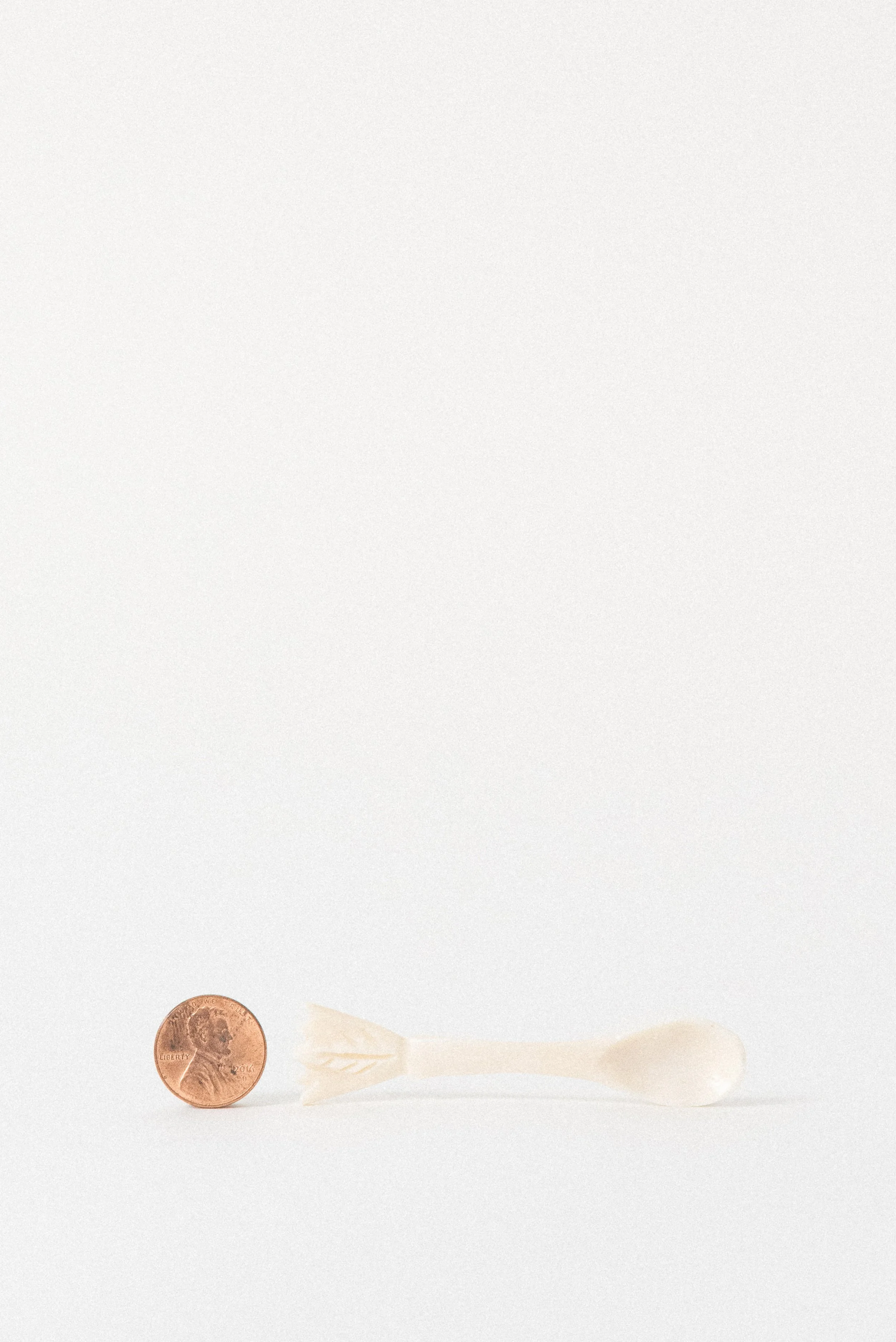 Side view of a hand-carved Egyptian camel bone spoon with natural bone texture and carved arrow detail.