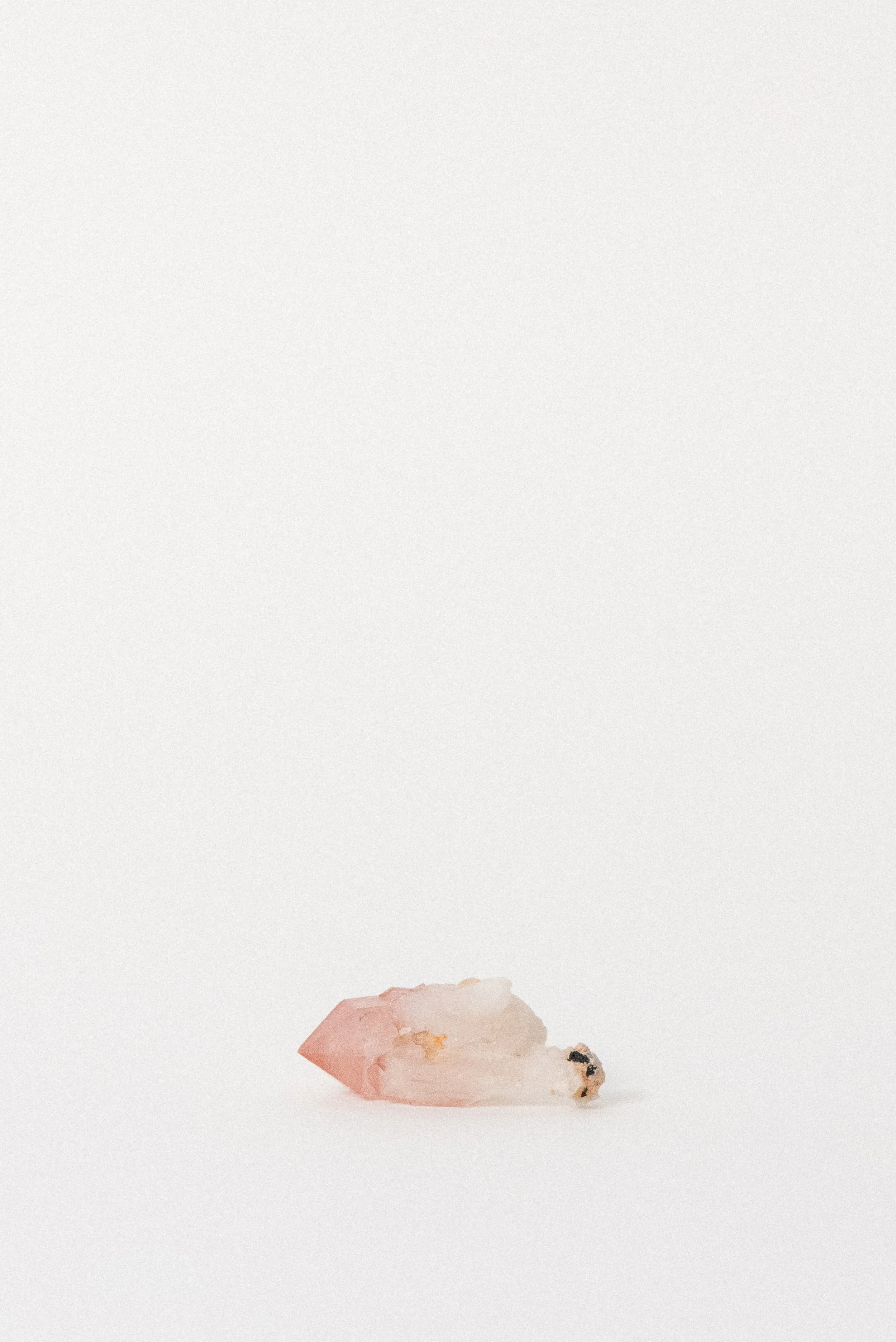 Close-up of Pink Quartz point with hematite inclusions and light matrix at base