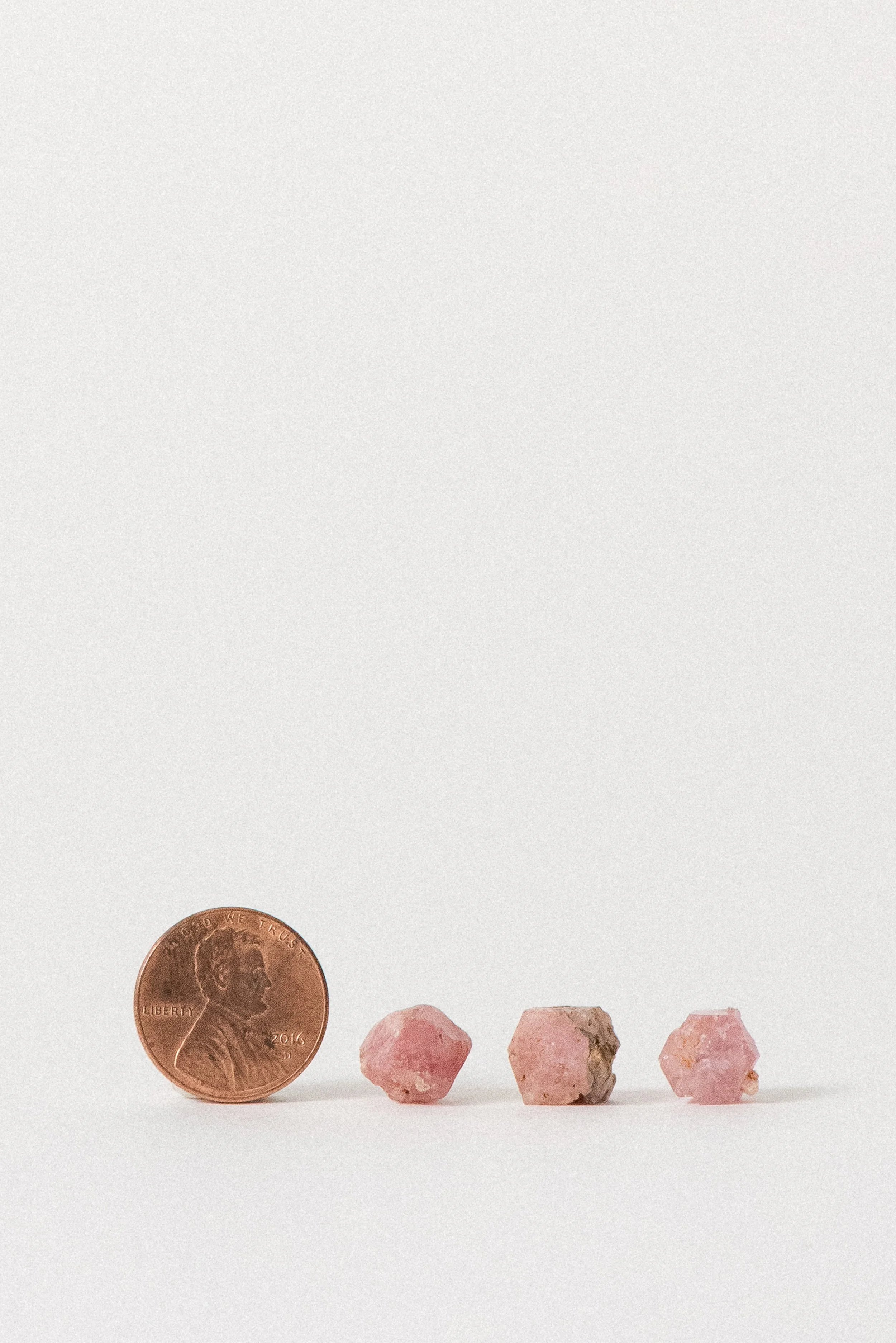 Small pink garnet crystals from Xalostoc, Mexico shown next to a penny for size reference