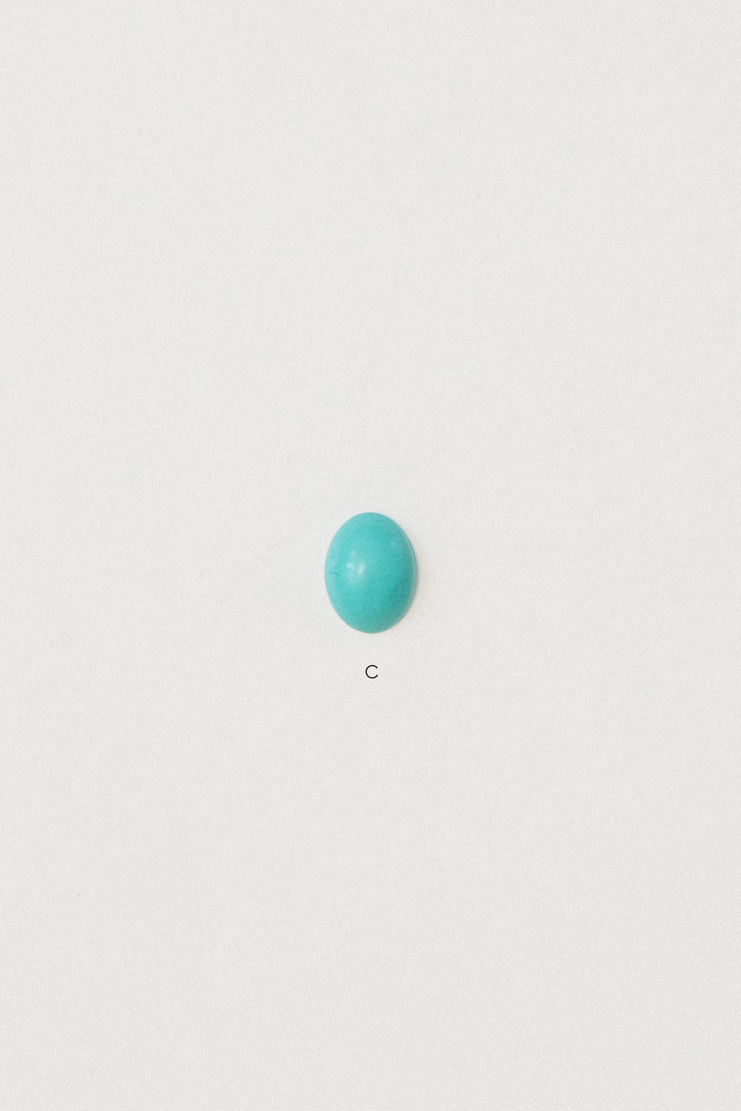 Natural turquoise cabochon from Sinai, Egypt labeled C on a white background.
