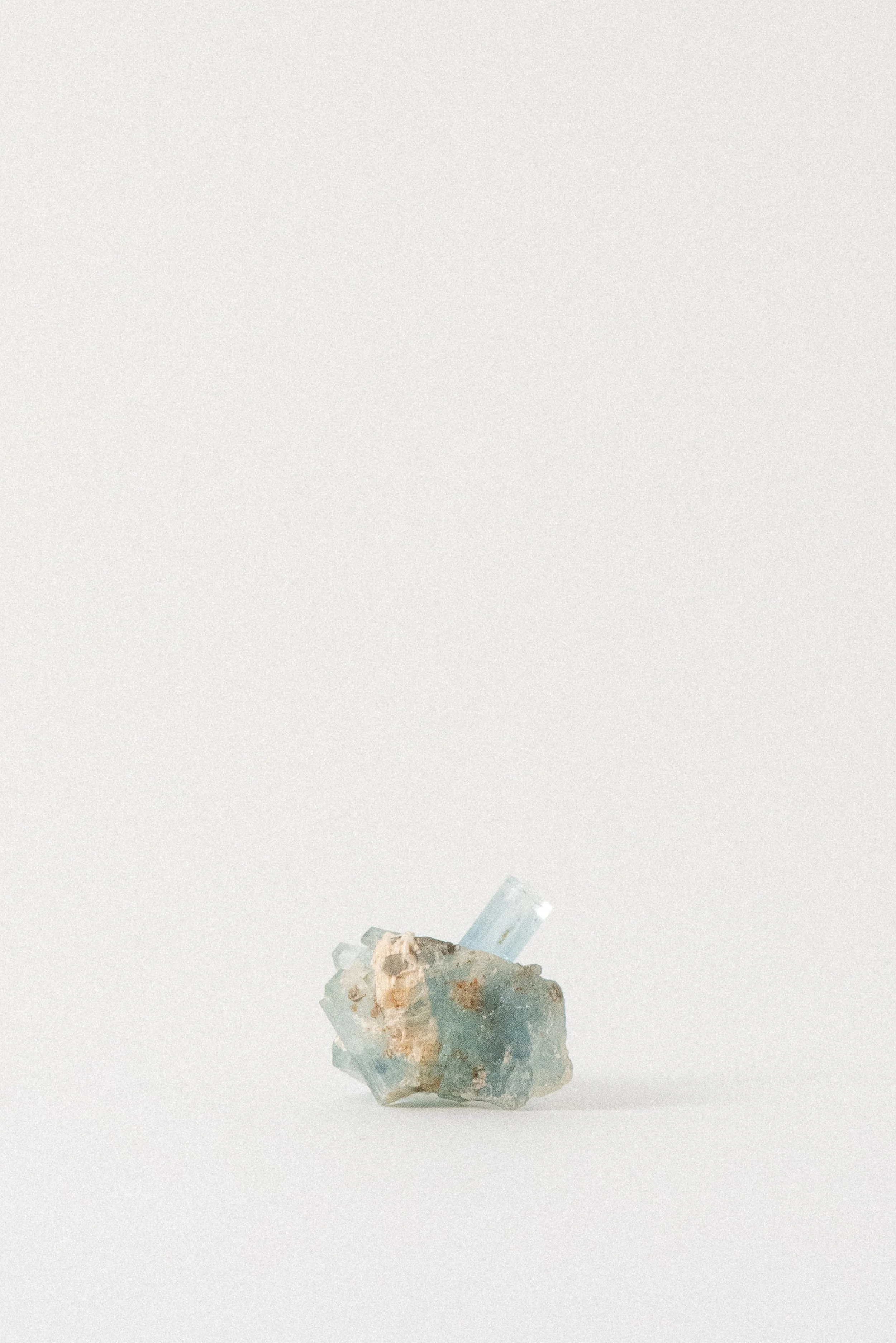Aquamarine crystal from Erongo Mountain, Namibia, with pale blue clarity and earthy matrix on a neutral background