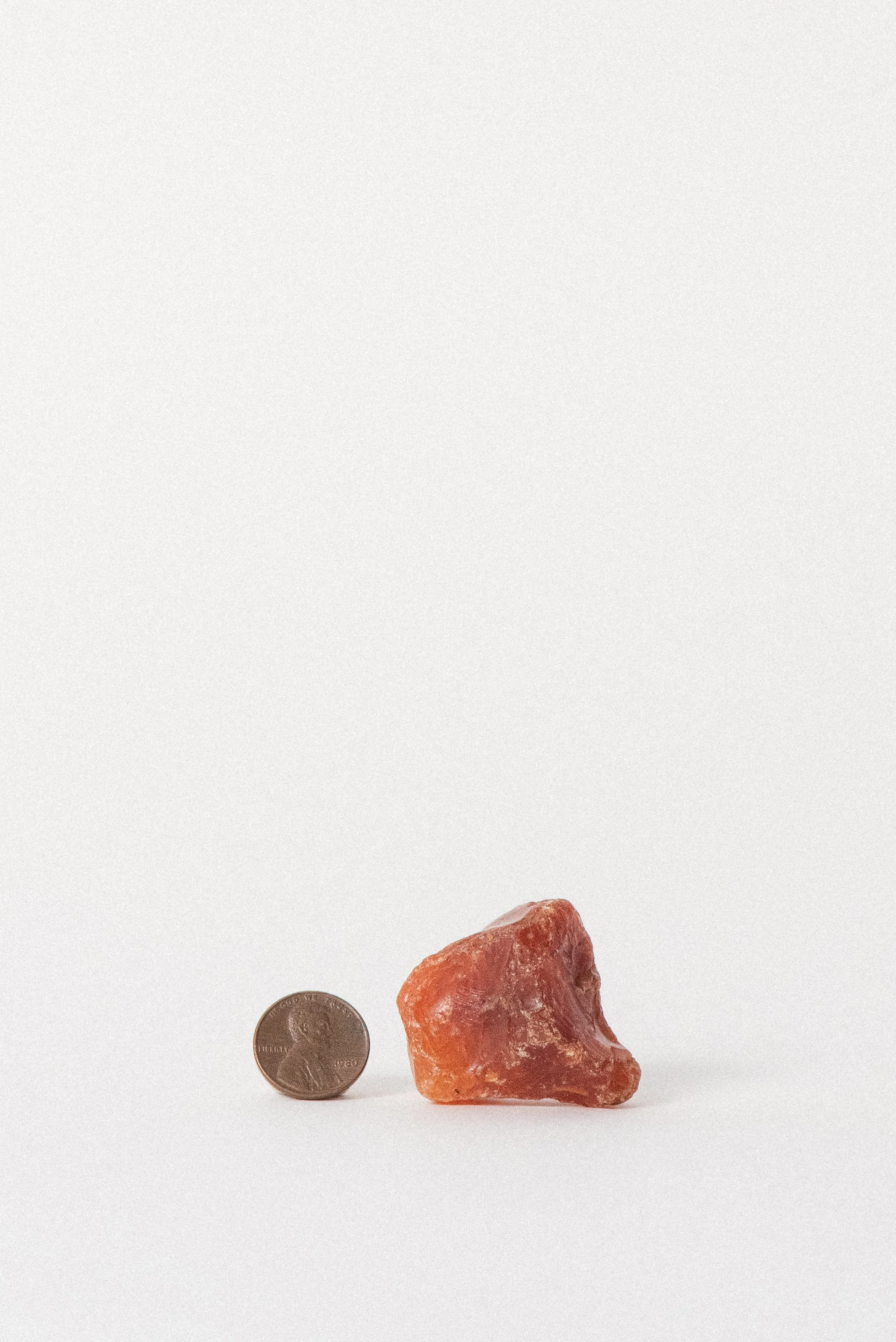 Carnelian next to a penny for scale, showing organic shape and vintage surface.