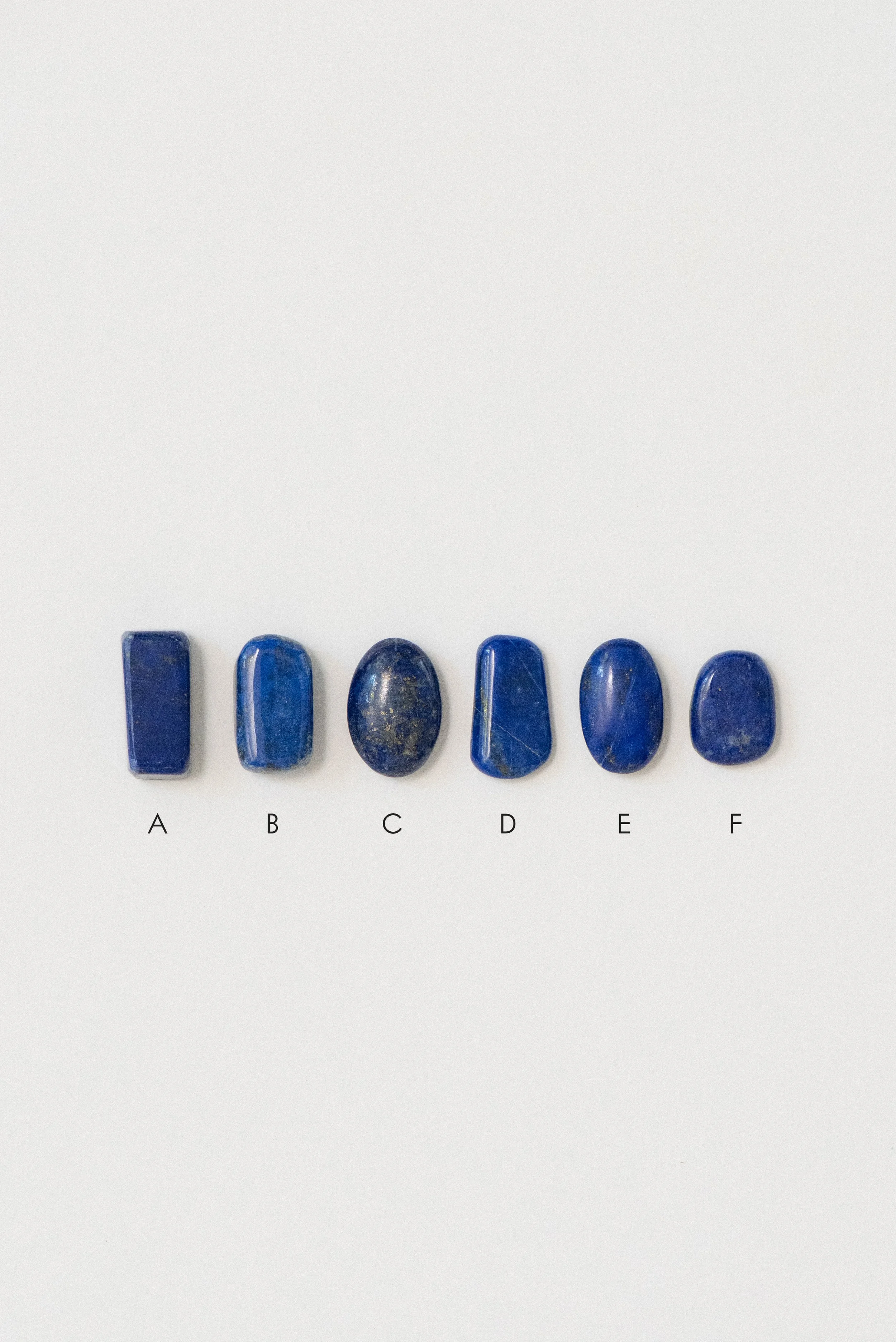 Six natural lapis lazuli polished stones from Afghanistan displayed on a white background, labeled A through F for individual selection.