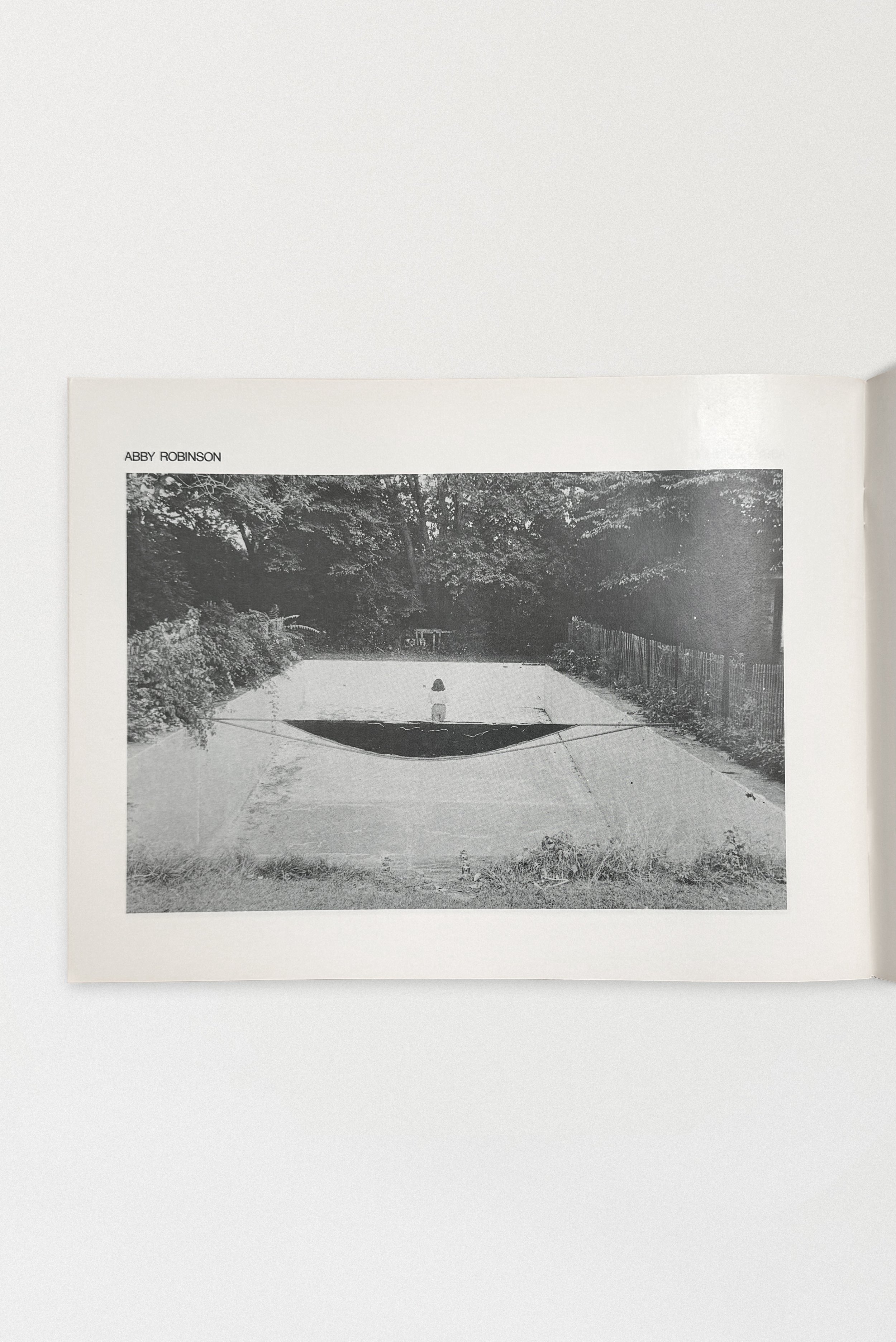 Abby Robinson’s haunting contribution to the Pool project (1976–1979) captures a solitary figure in an abandoned pool, a surreal meditation on emptiness, form, and suburban decay.