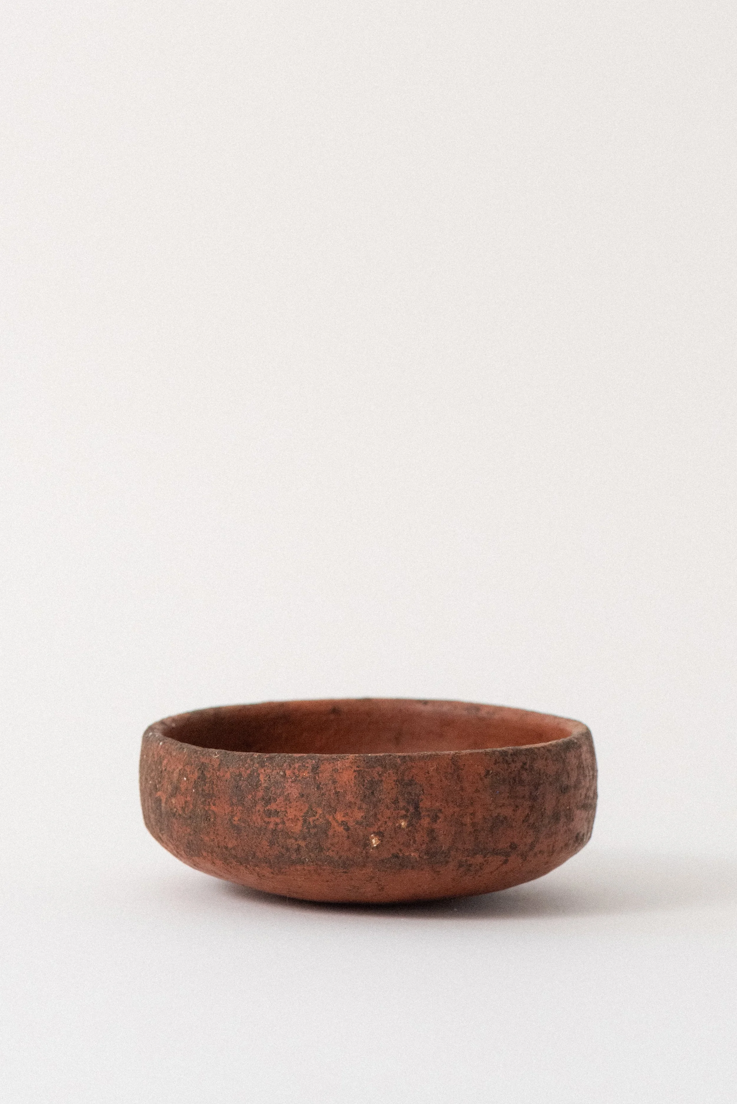 Rustic red clay pottery bowl handcrafted in Oaxaca, side view on white background