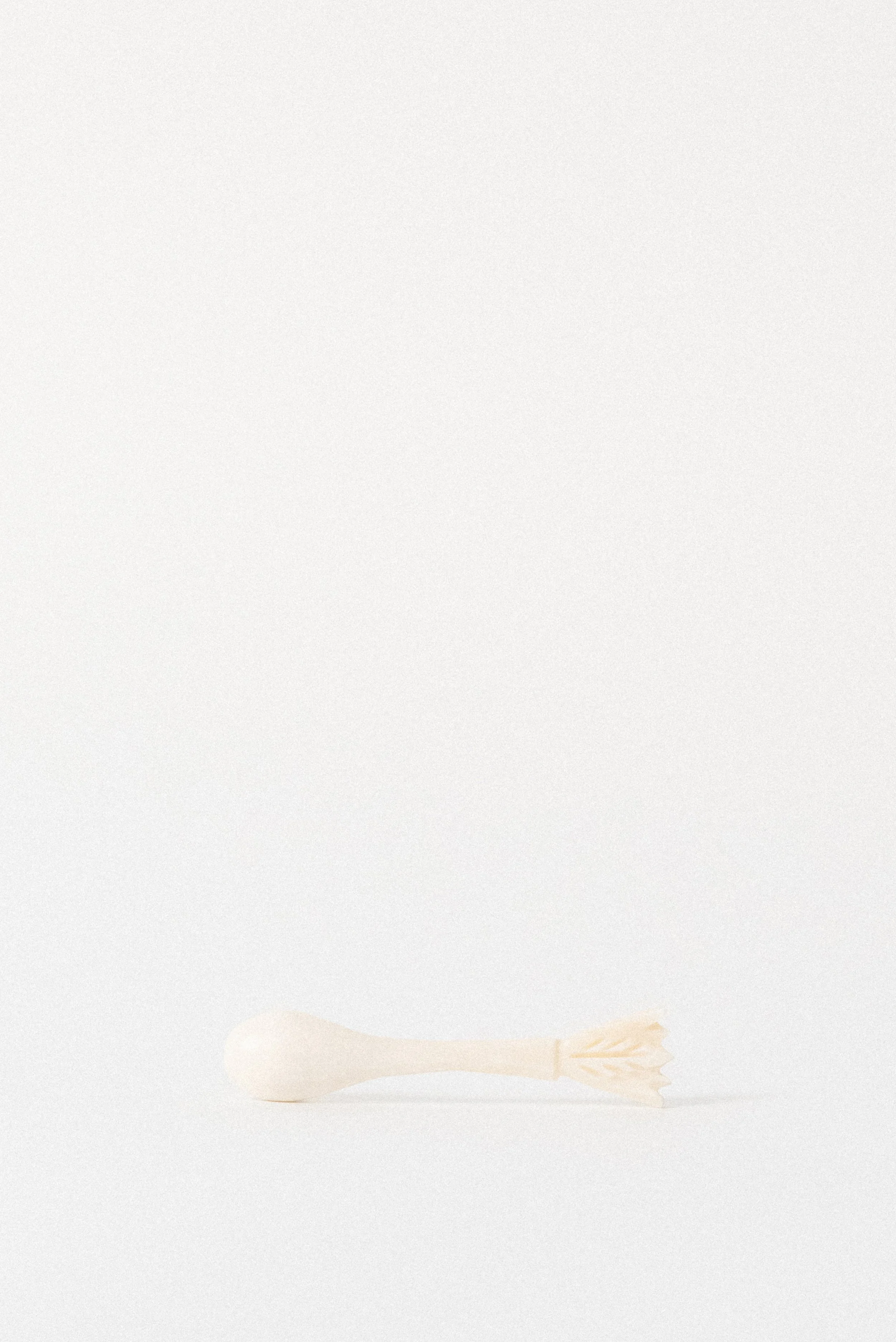 Hand-carved Egyptian camel bone spoon shown next to a penny for scale, highlighting petite size and intricate carving.