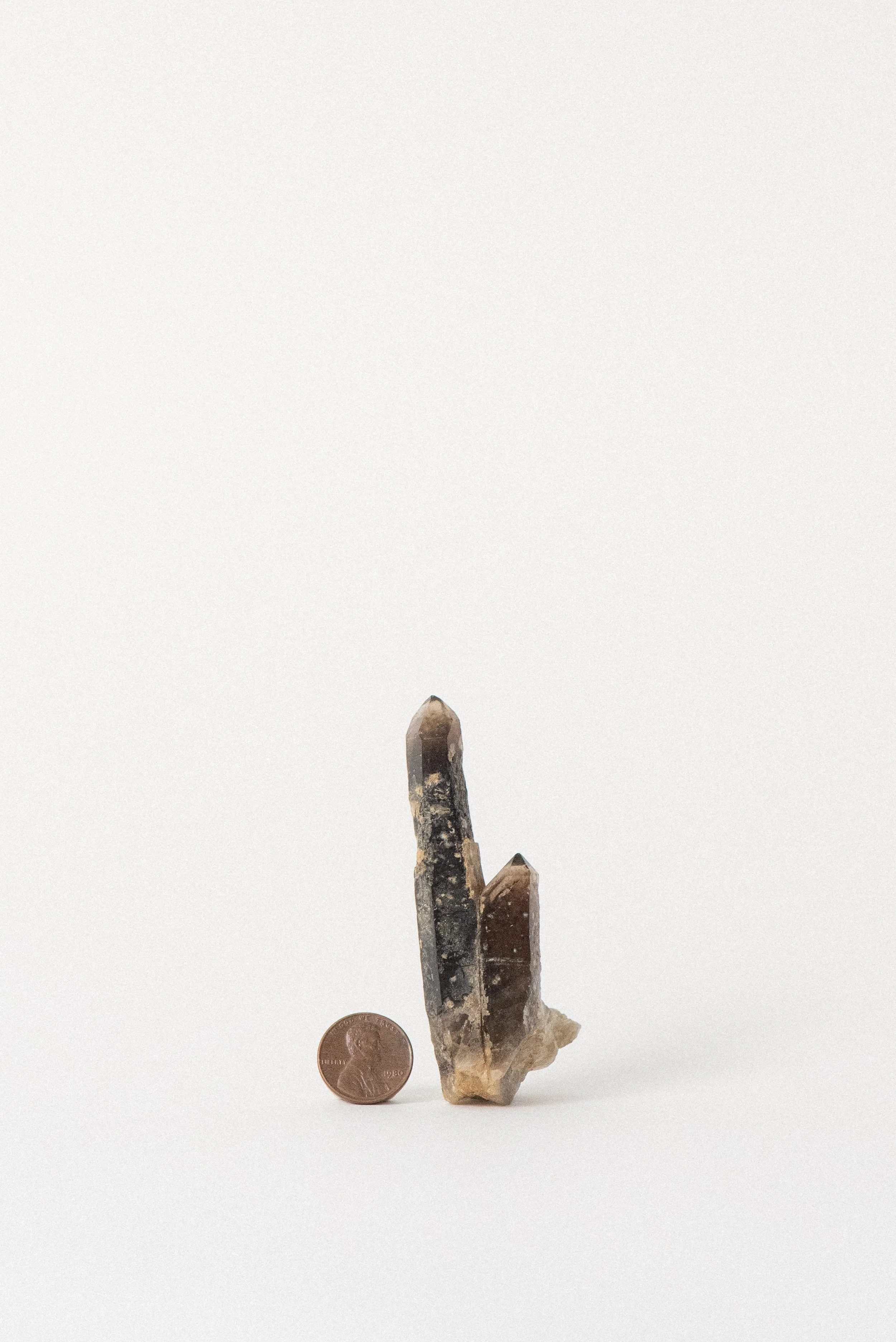 Smoky quartz specimen with penny for scale, tall crystal formation from Hallelujah Junction.