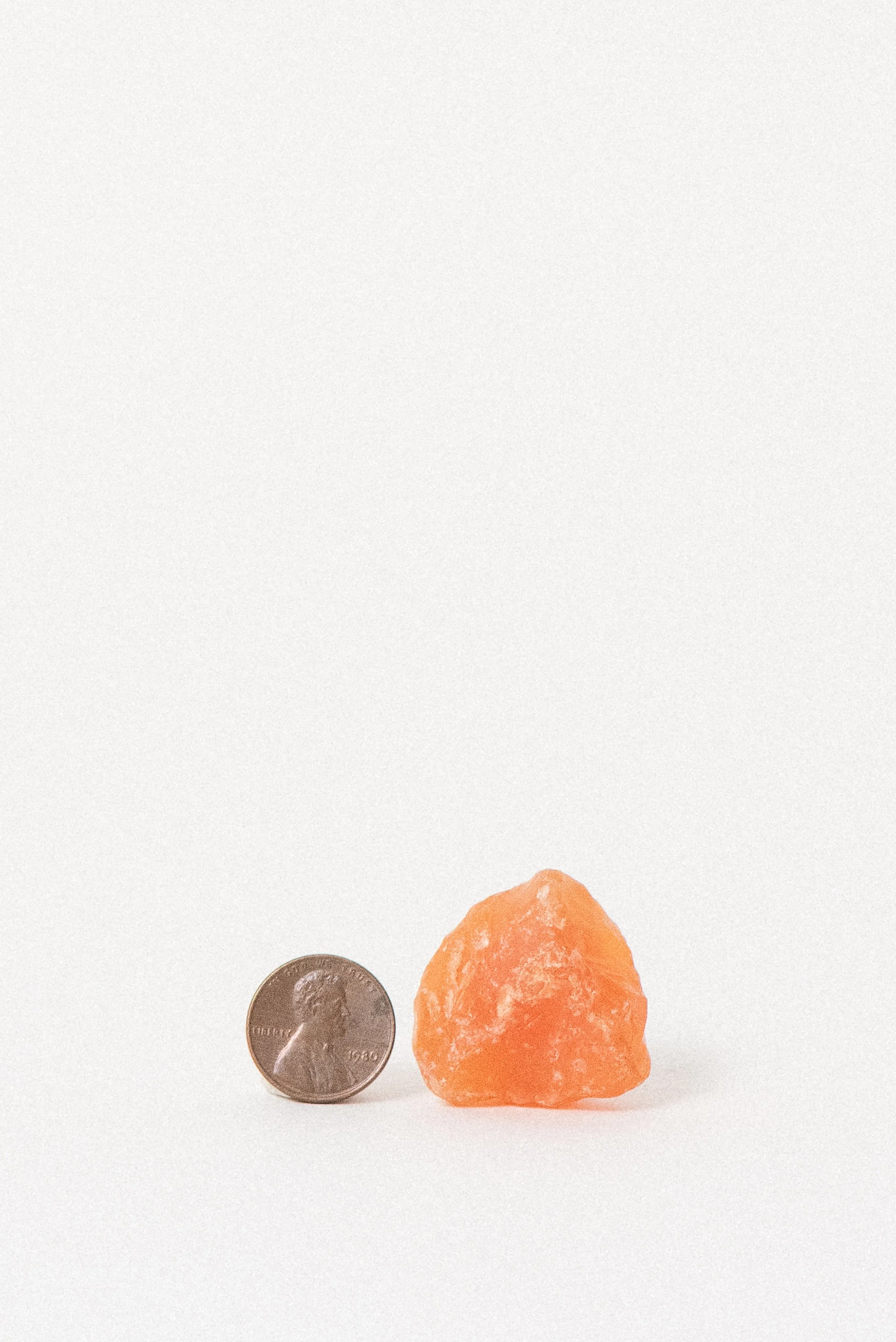 Raw African carnelian crystal with U.S. penny for size comparison