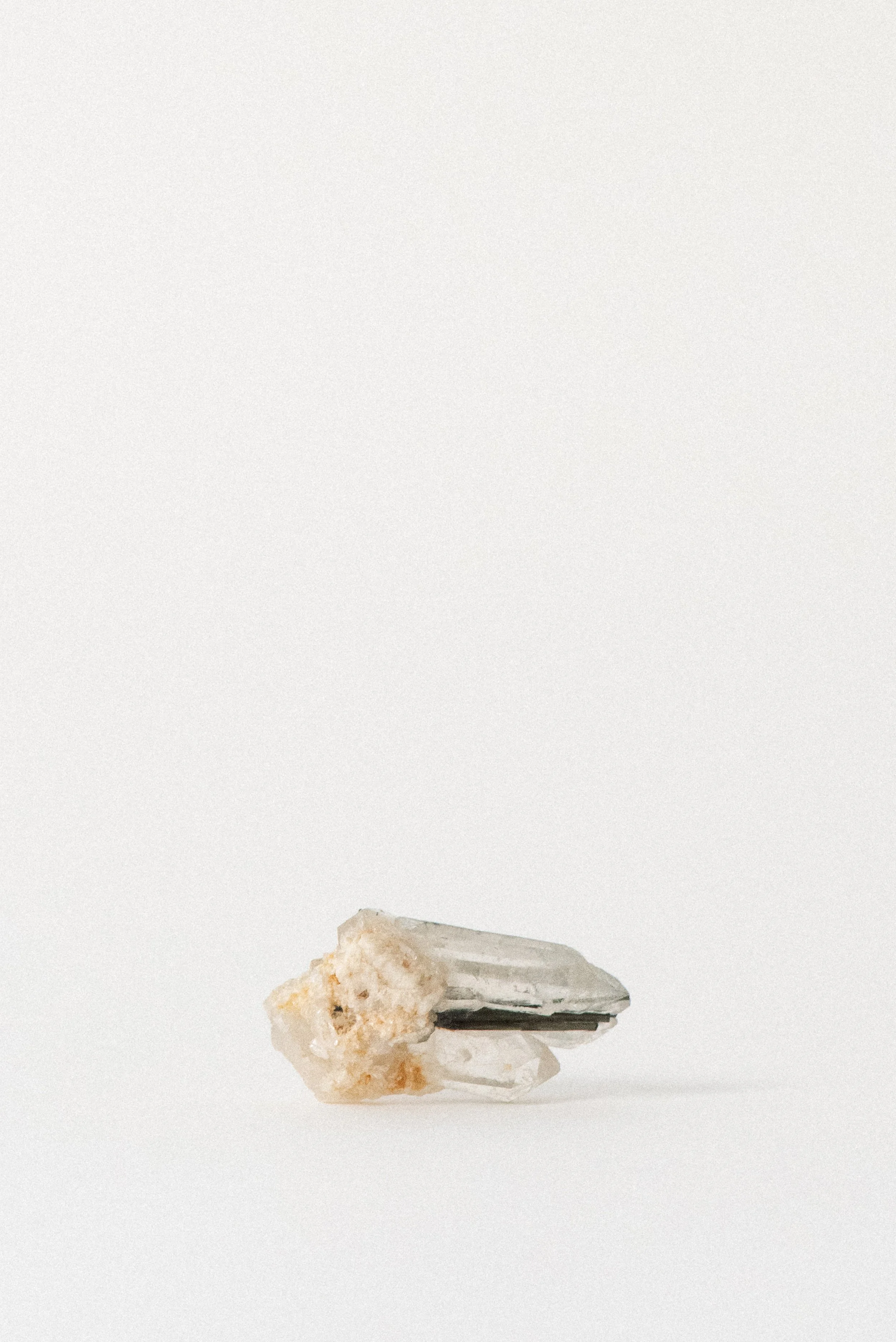 clear quartz point featuring dark tourmaline inclusions, balancing energy flow.
