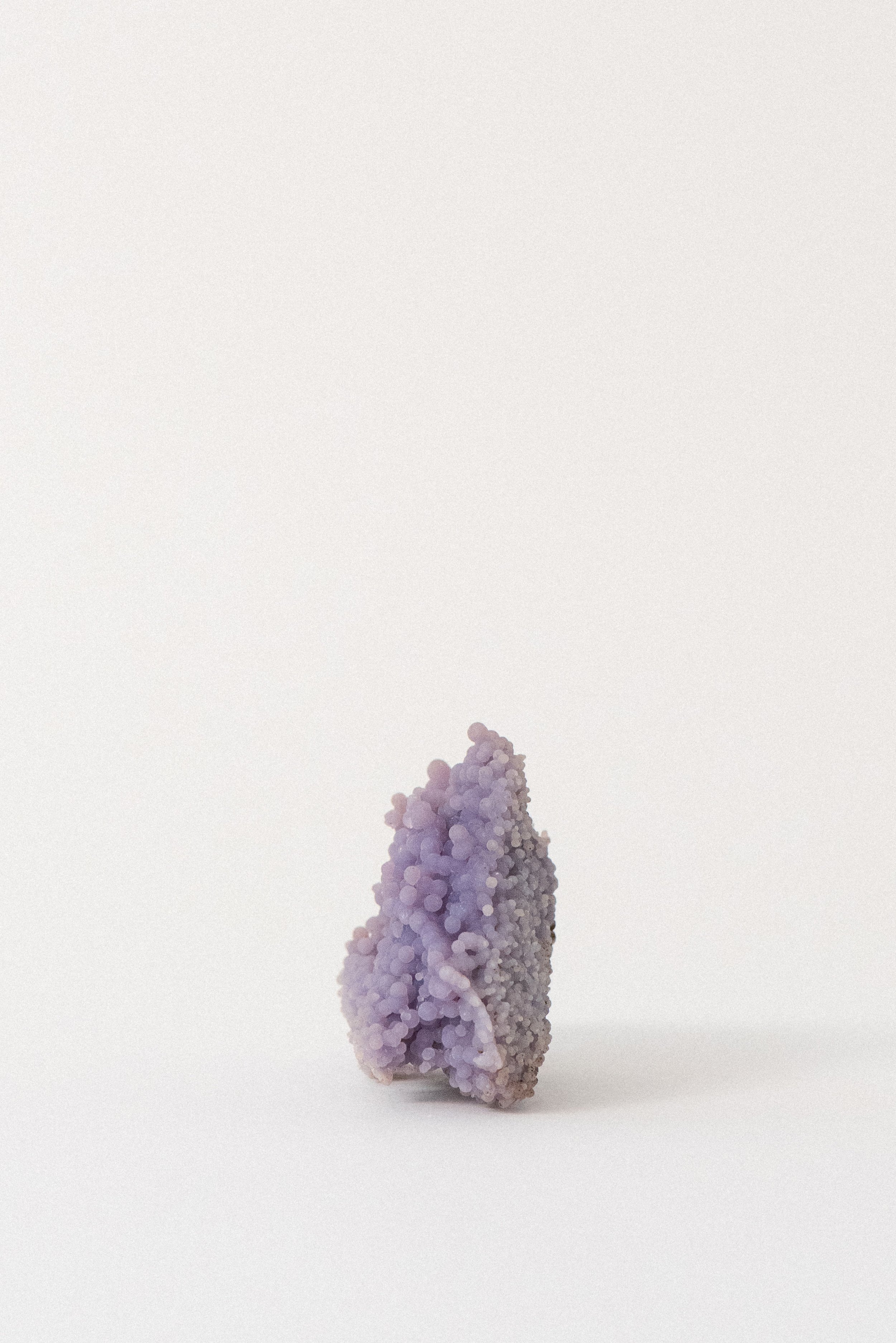 Standing cluster of purple grape agate with spherical botryoidal texture from Sulawesi, Indonesia, photographed on a soft white background.