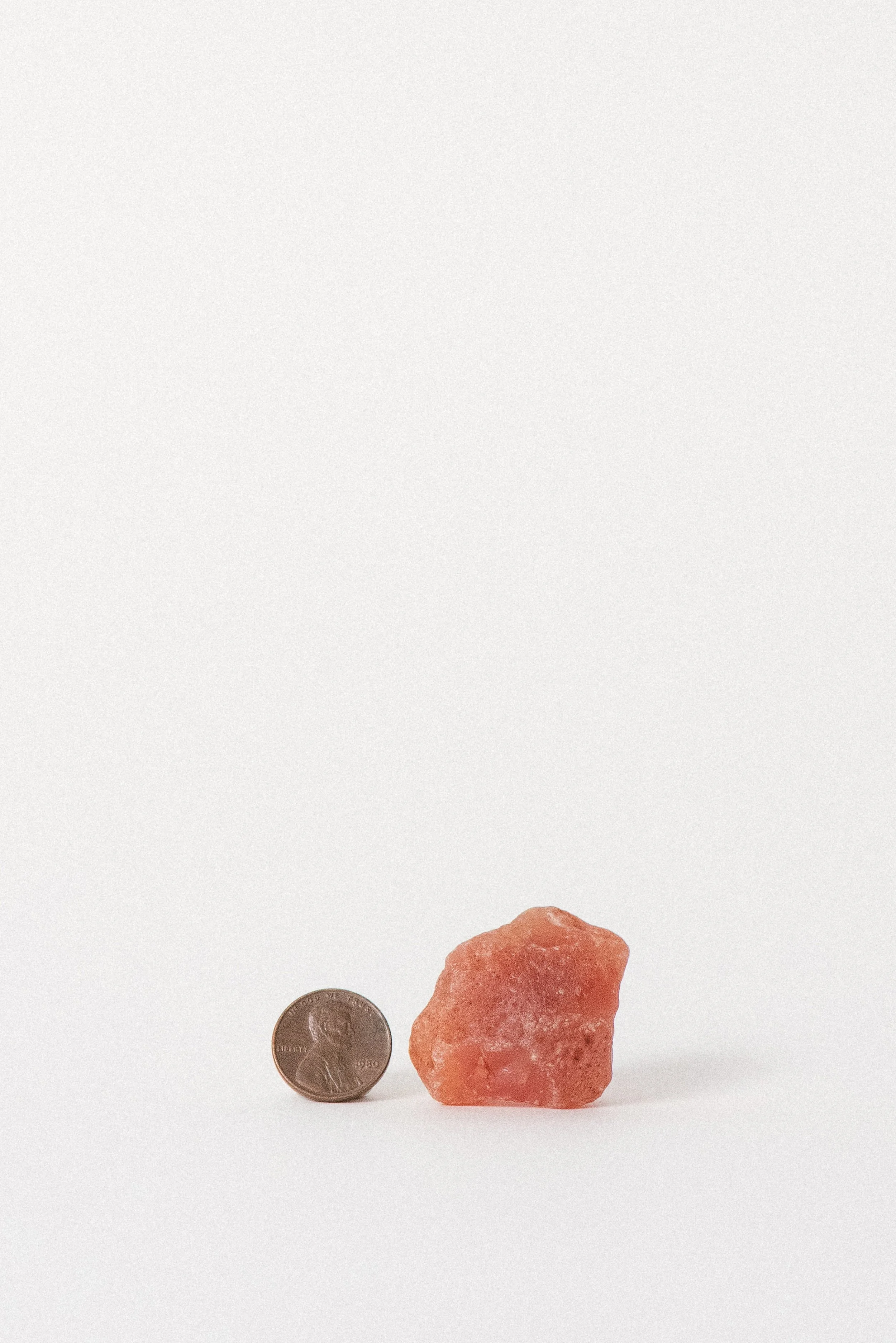 Carnelian next to a penny for scale, revealing its organic, unpolished form.