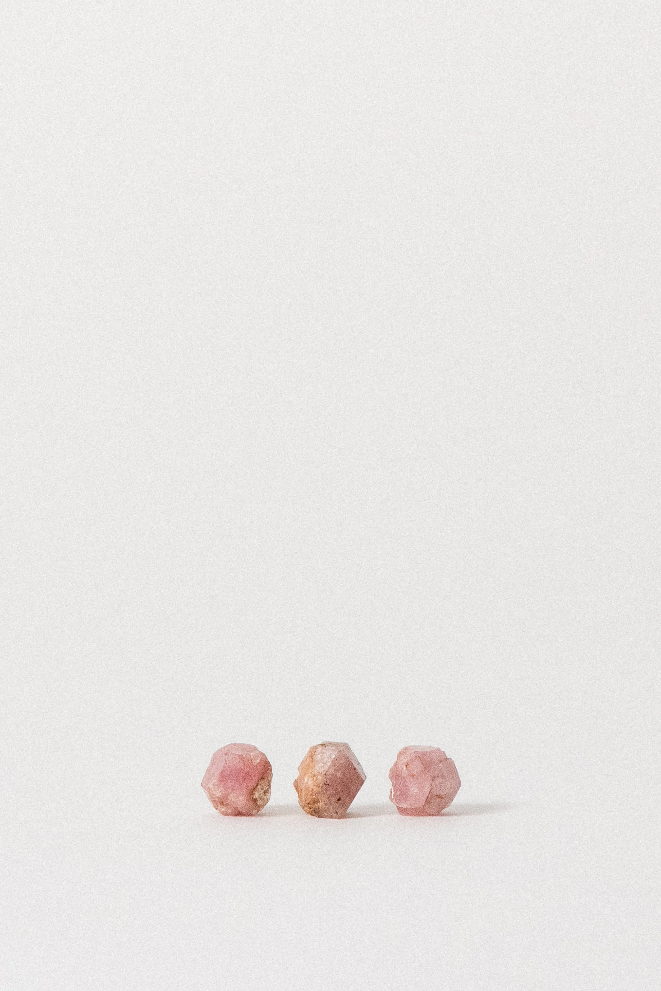 Cluster of raw pink garnet crystals from Xalostoc, Mexico on white background