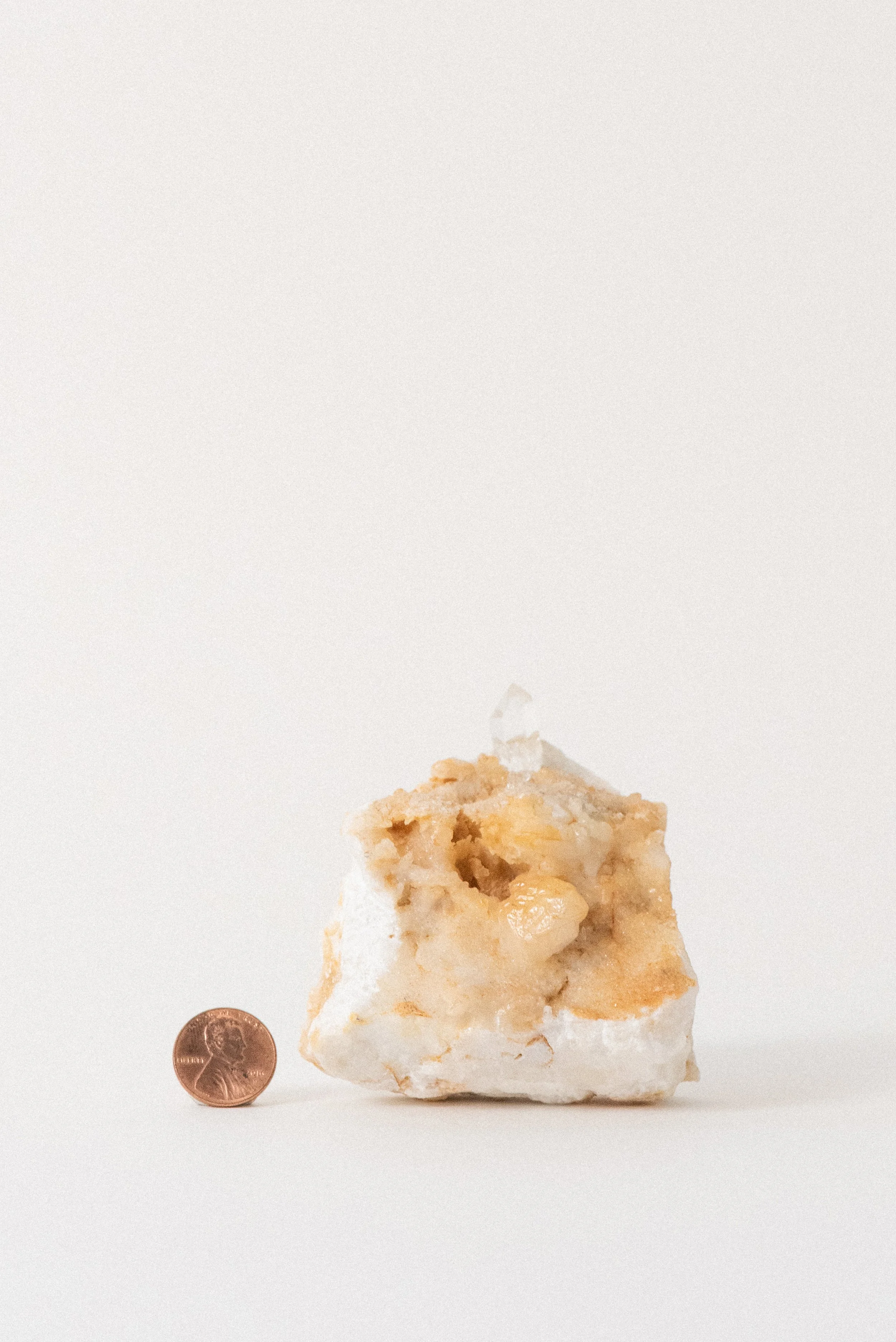 Quartz crystal on Carrara marble matrix from La Facciata Quarry, shown with a penny for scale, photographed for Crystal Voyager’s online shop.