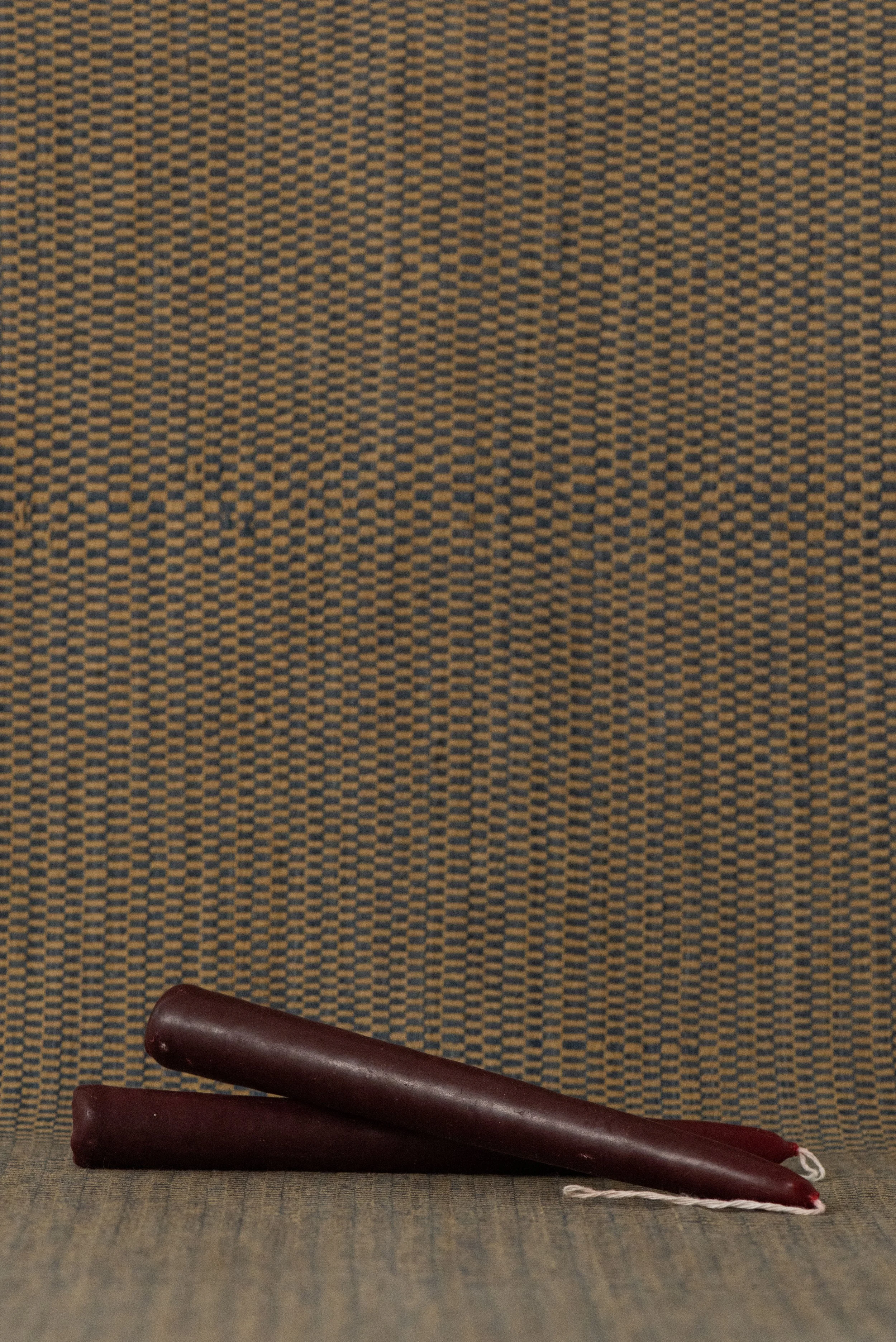 Set of two hand-dipped red beeswax candles from Oaxaca, displayed on a woven textile background.