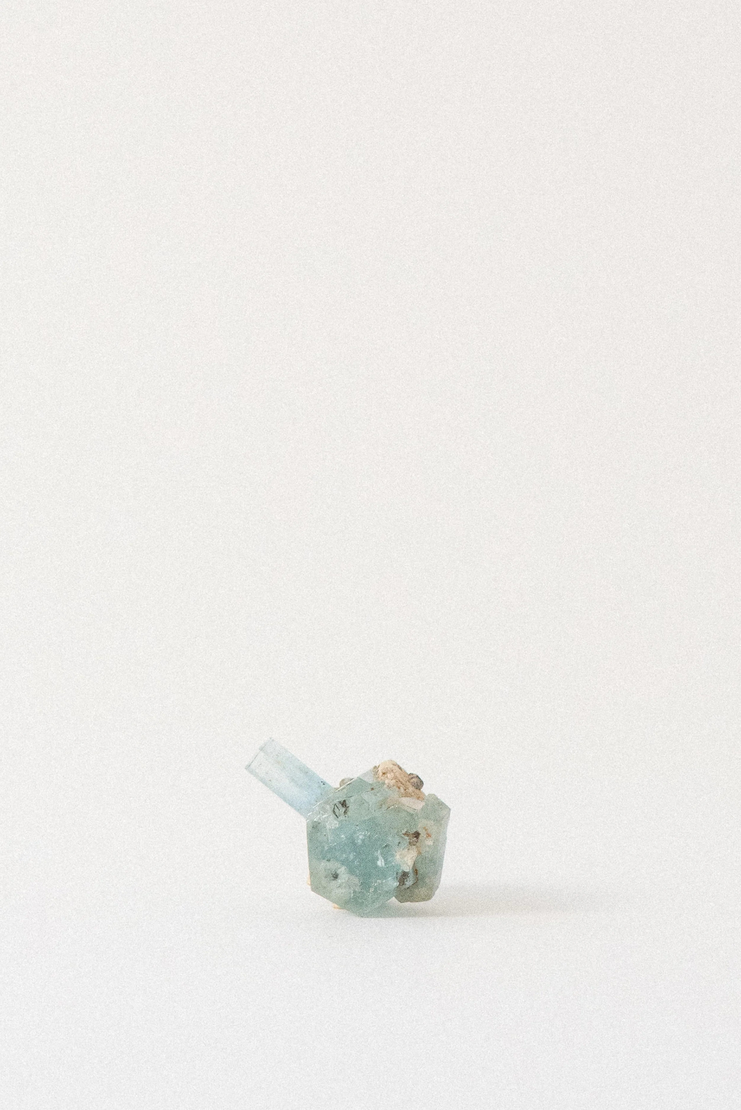 Aquamarine crystal from Erongo Mountain, Namibia, with upright blue termination and matrix on white background