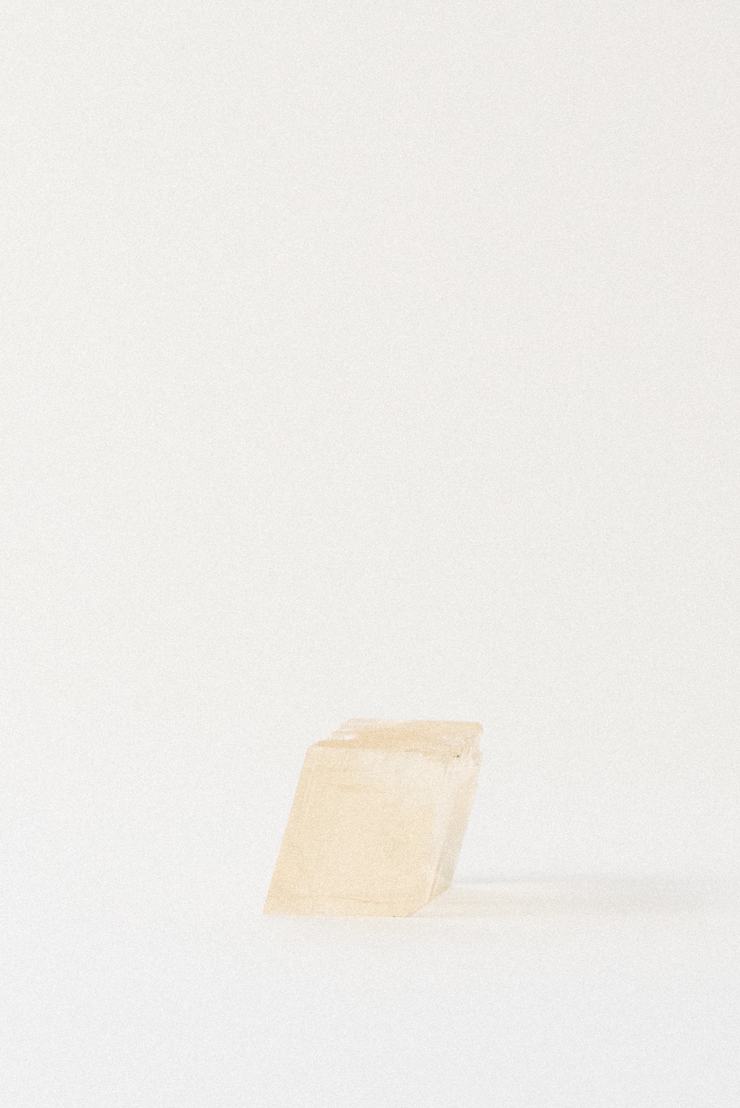 Yellow optical calcite rhomboid crystal from Aurangabad, India, photographed in soft natural light on a minimal white background