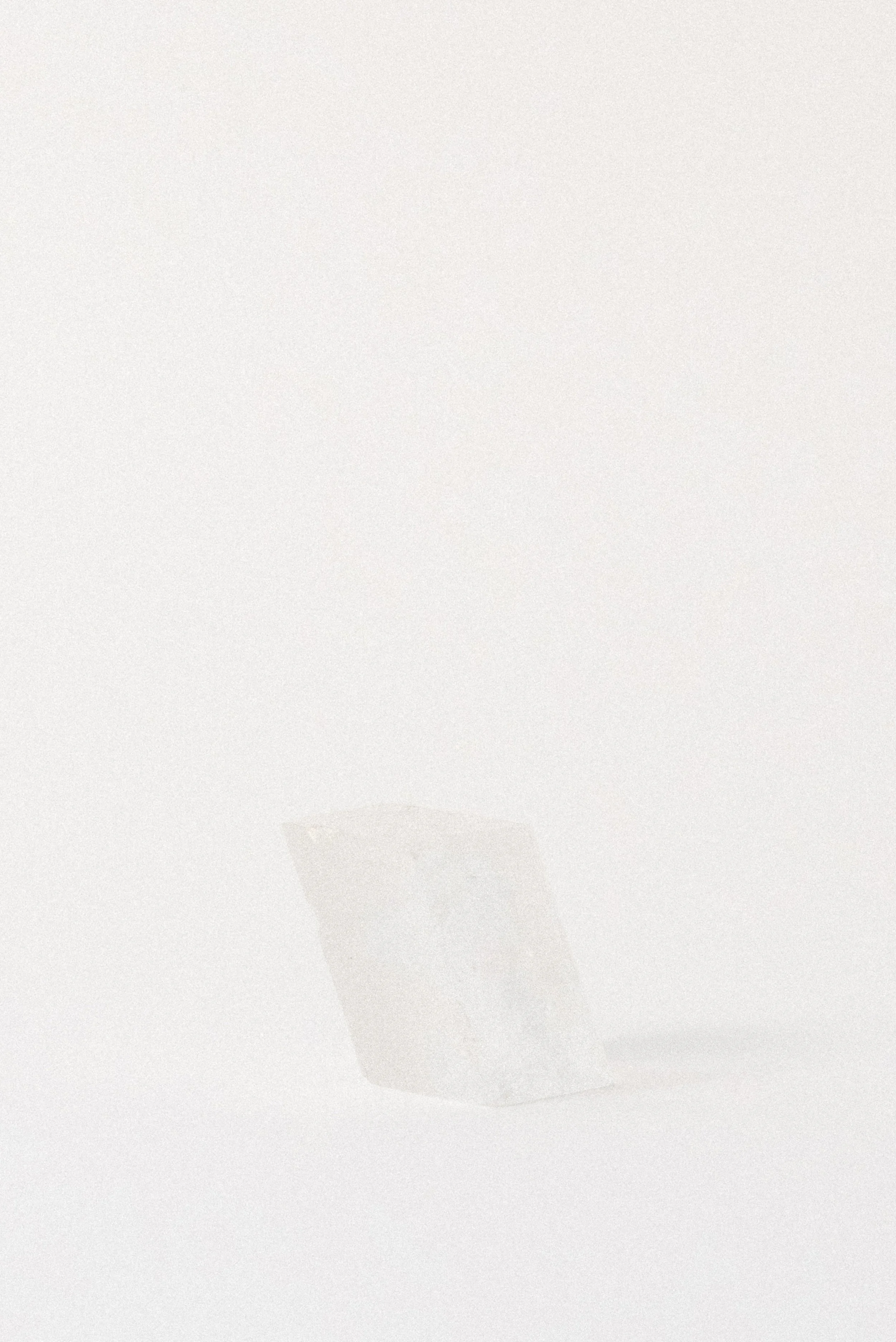Transparent optical calcite crystal in a rhomboid shape from Durango, Mexico, displayed upright on a white background.