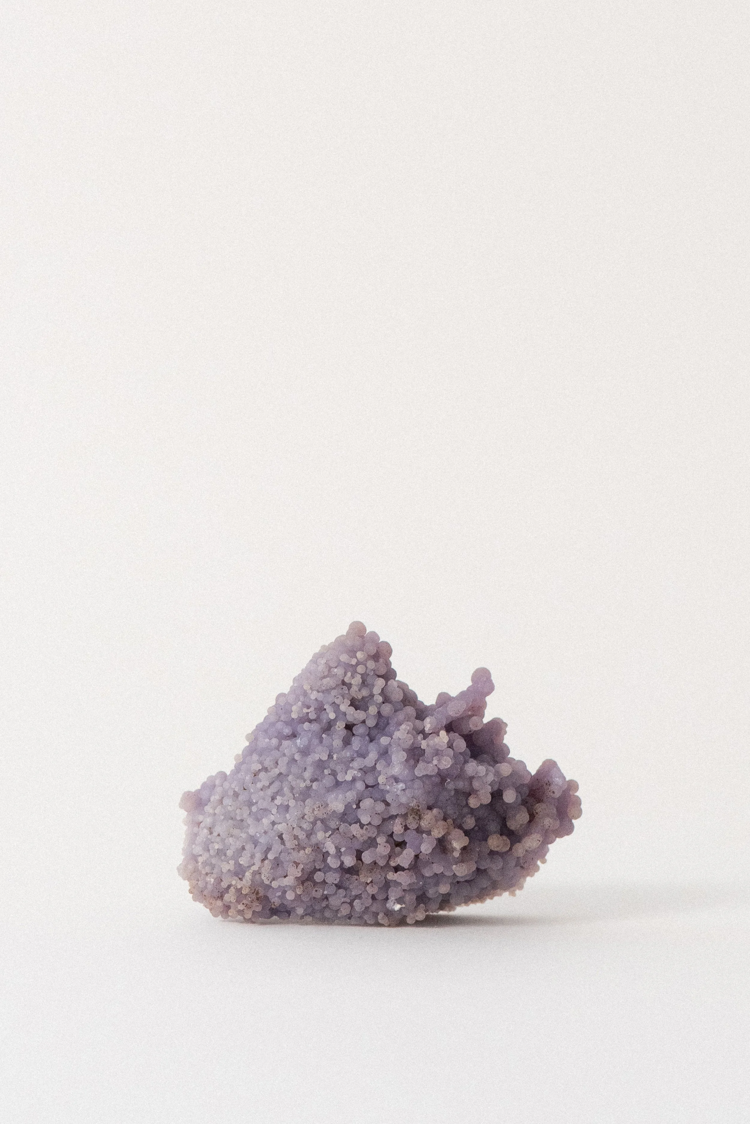 Detailed view of a purple grape agate crystal cluster from Sulawesi, Indonesia, featuring a smooth, rounded botryoidal surface and lilac hues.