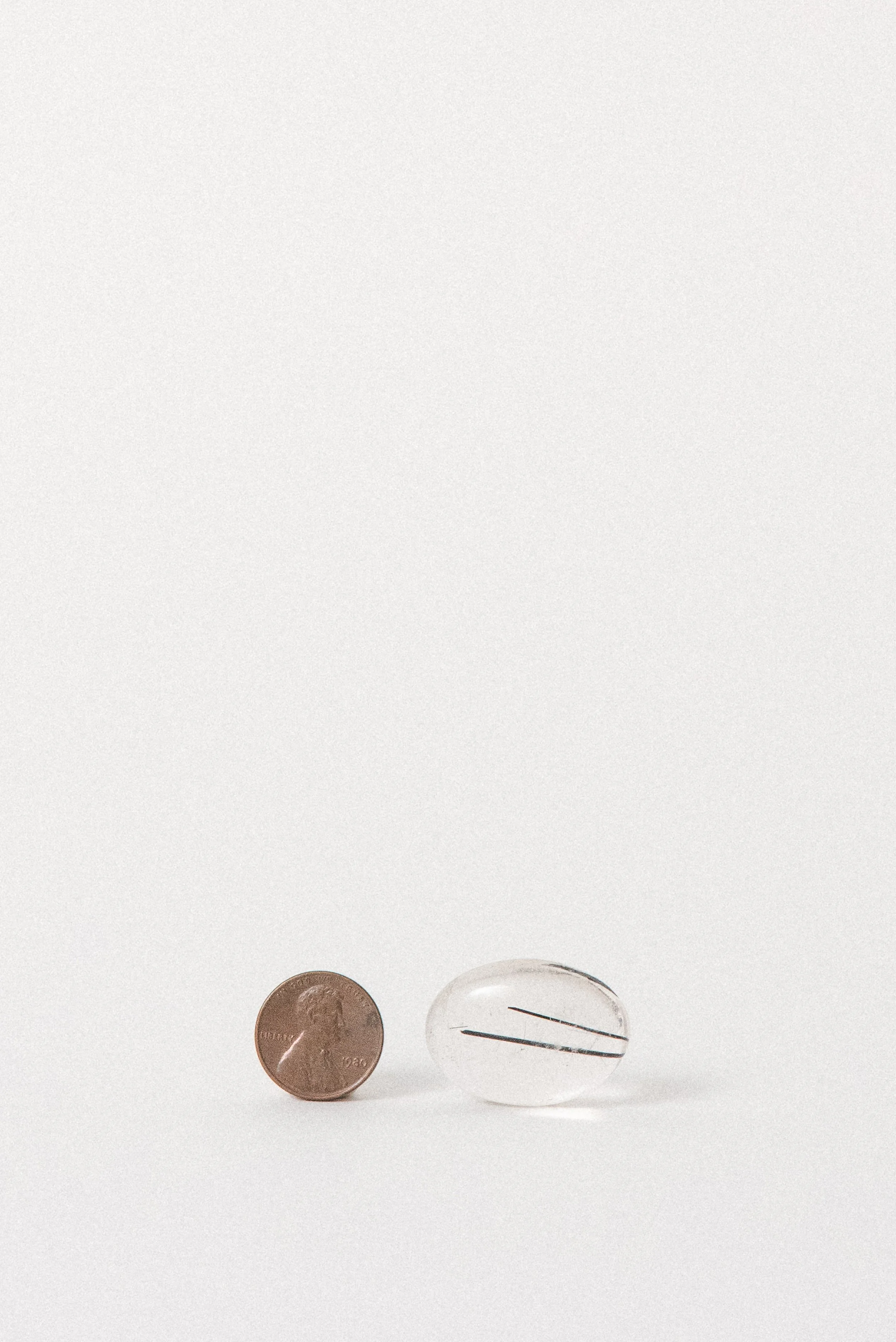 Tourmalinated quartz cabochon from Brazil, displayed with penny for scale.