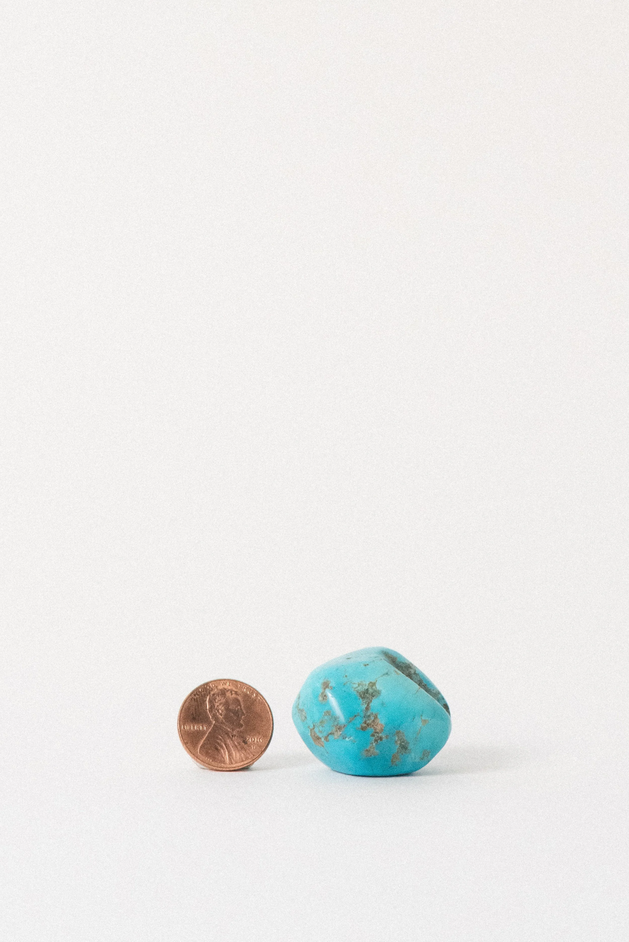 Egyptian turquoise stone with penny for size comparison, natural matrix visible