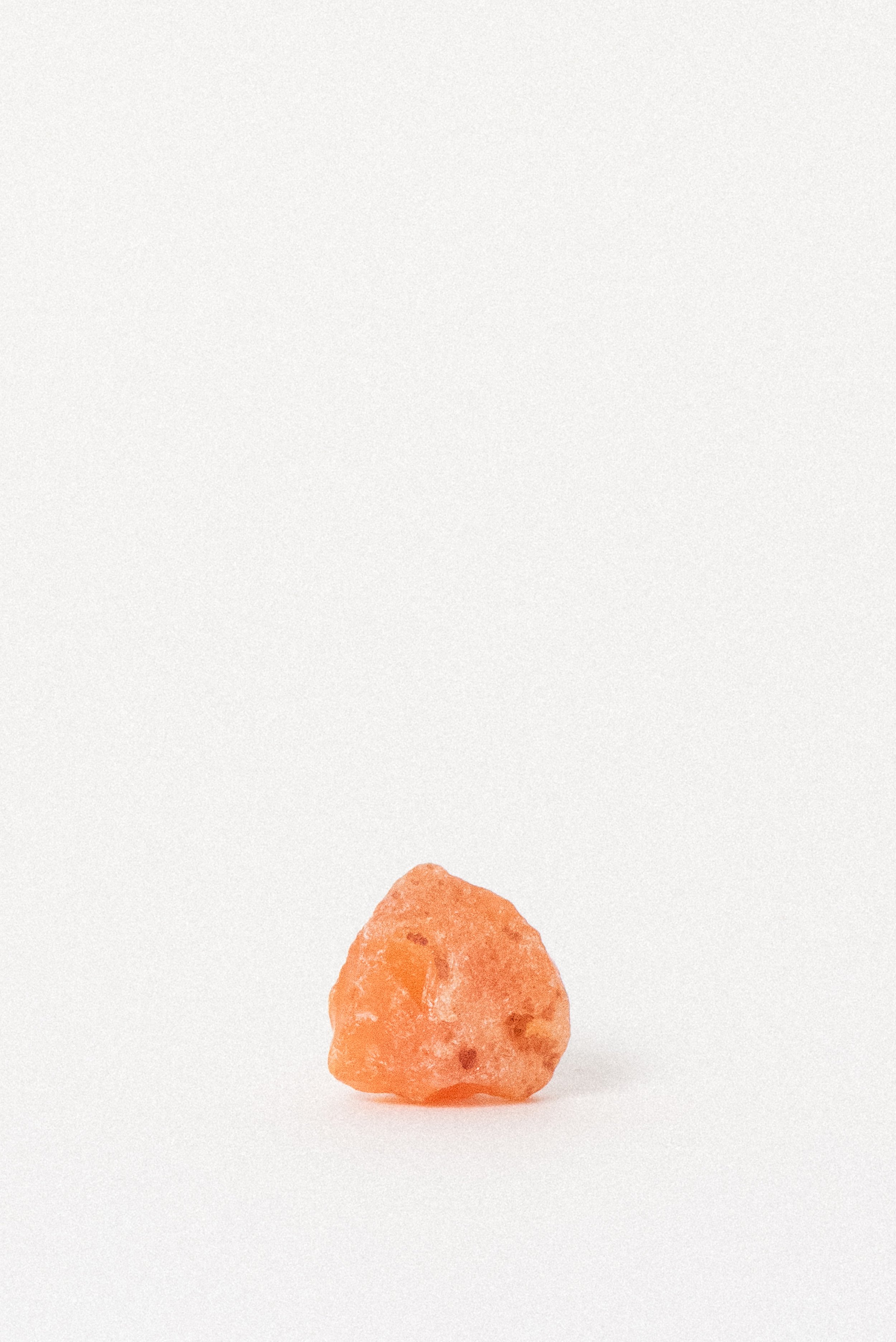 Vintage raw carnelian crystal in orange tones, photographed on white background