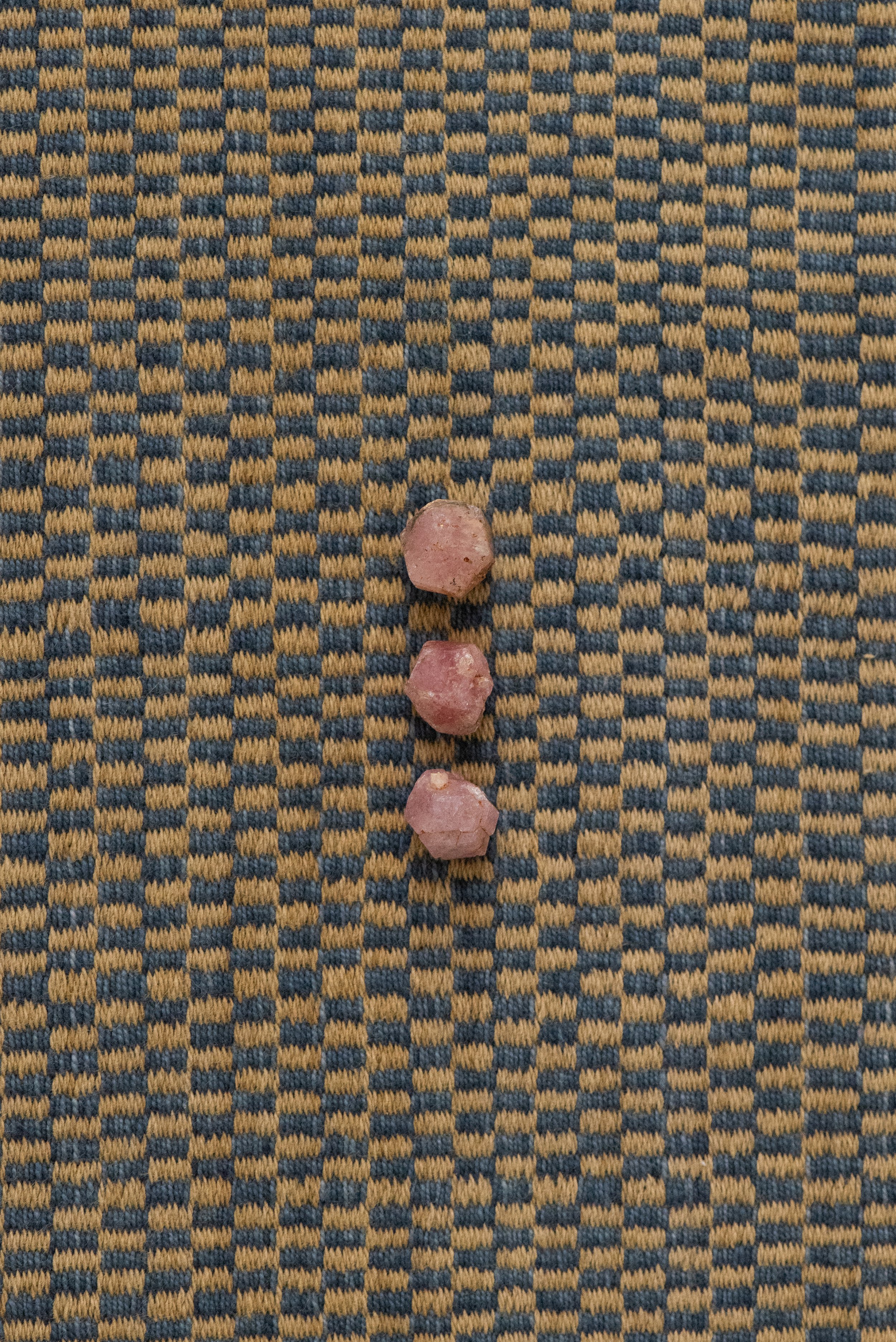 Raw pink garnet crystals from Xalostoc, Mexico displayed on patterned textile background