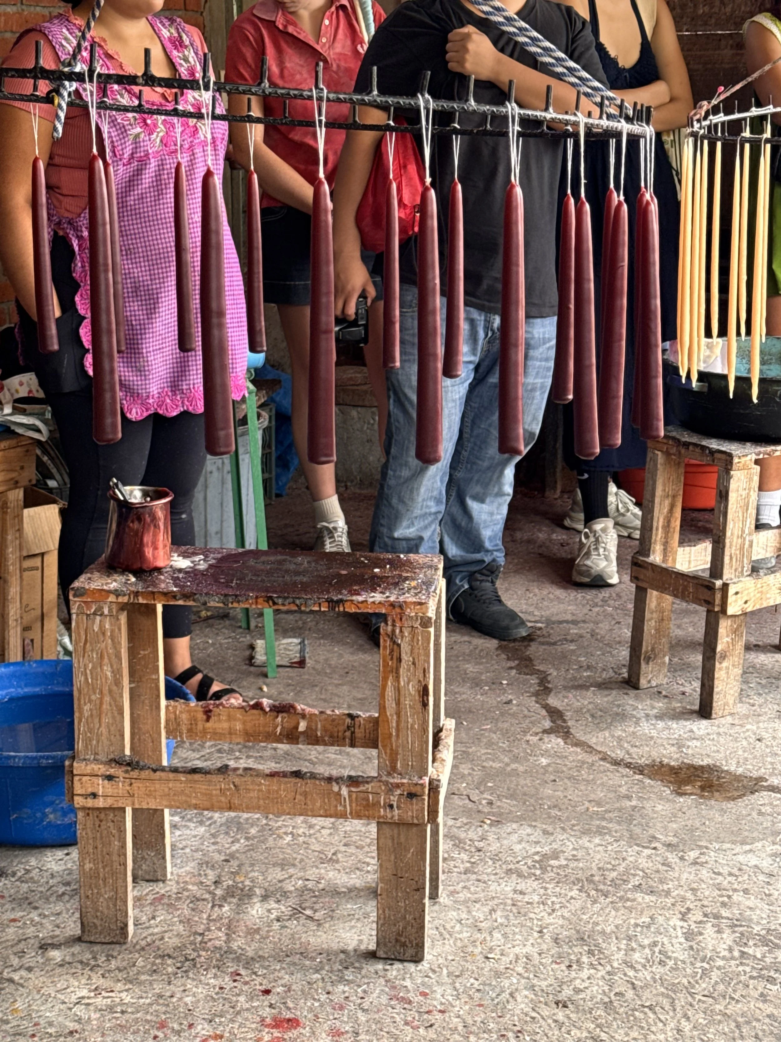 Freshly poured red taper beeswax candles hanging to dry in a Teotitlán del Valle workshop, part of Oaxaca’s centuries-old candle-making tradition