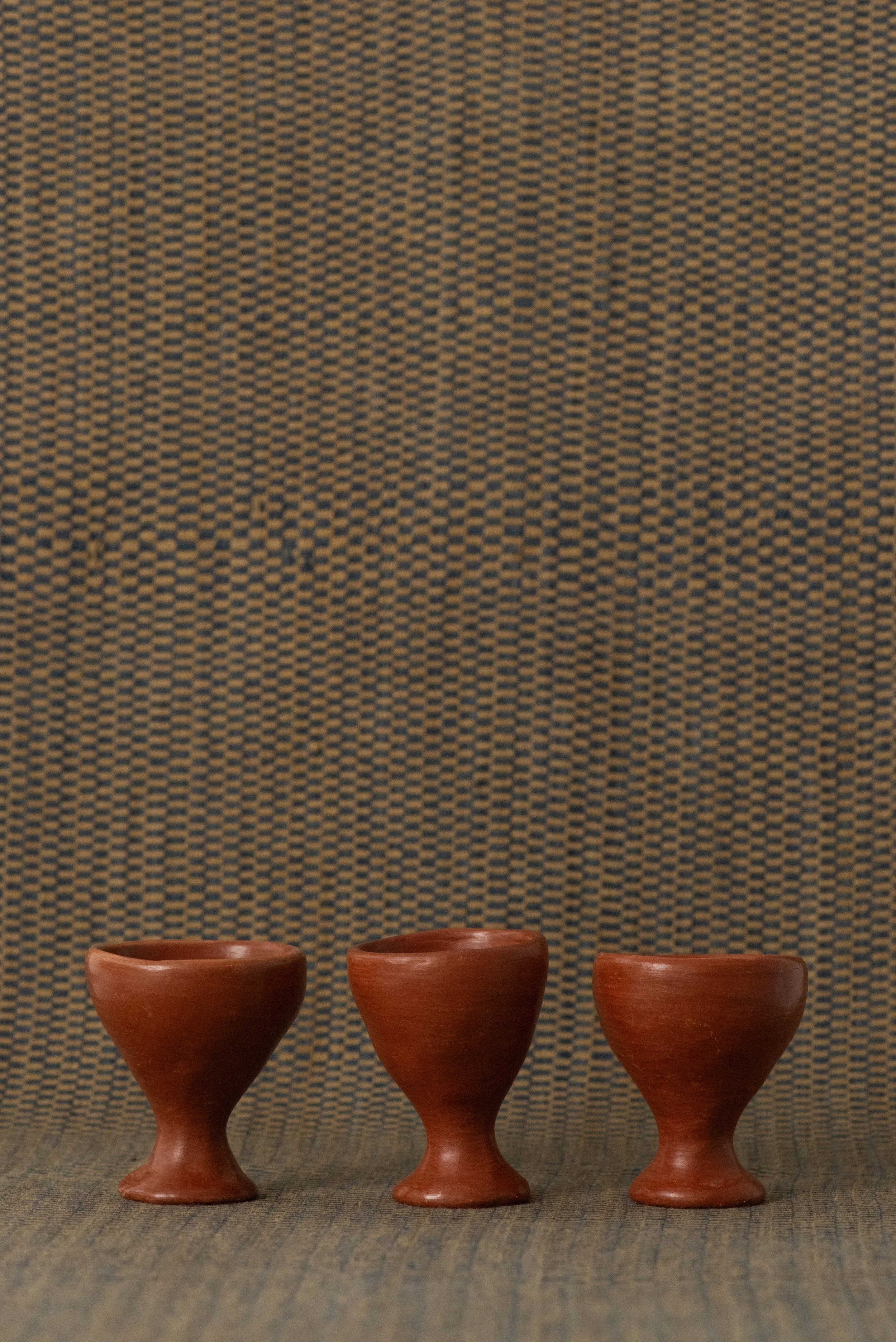 Set of three handmade Barro Rojo egg cups in natural red clay from Oaxaca, perfect for serving soft-boiled eggs or small bites.