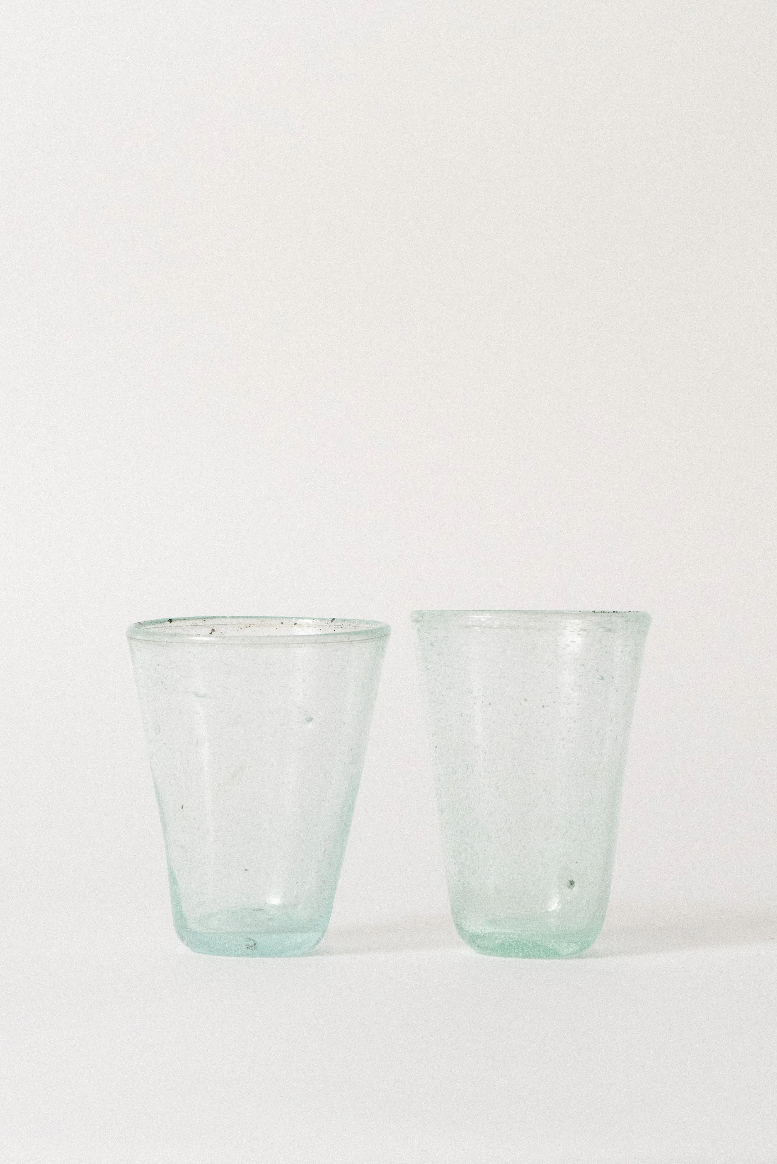 Angled view of two handblown Egyptian seed glass cups featuring natural air bubbles and irregular shape.