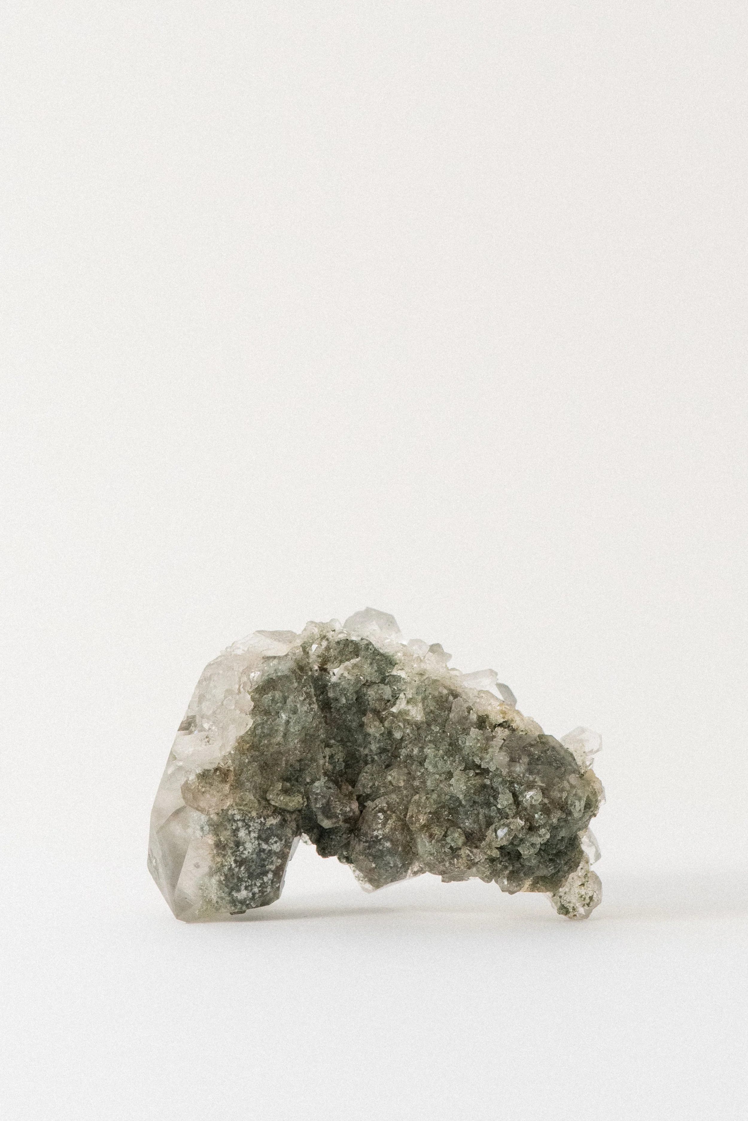 Himalayan quartz cluster with chlorite inclusions from Manihar, Kullu, Himachal Pradesh, India, showcasing its green mineral base and clear crystal points on a white background.