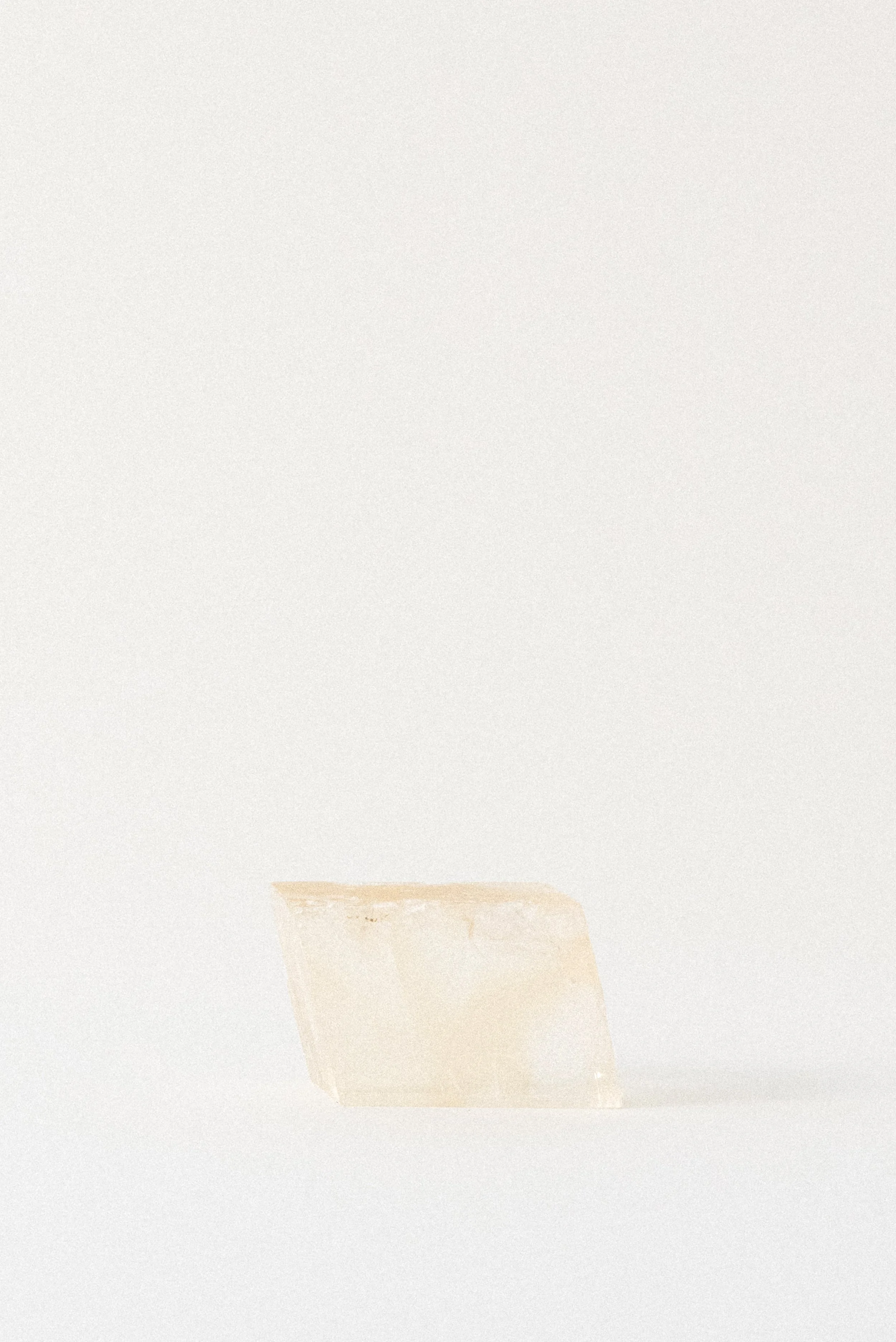 Translucent yellow calcite rhomboid from Aurangabad, India, photographed under soft studio lighting on a white background