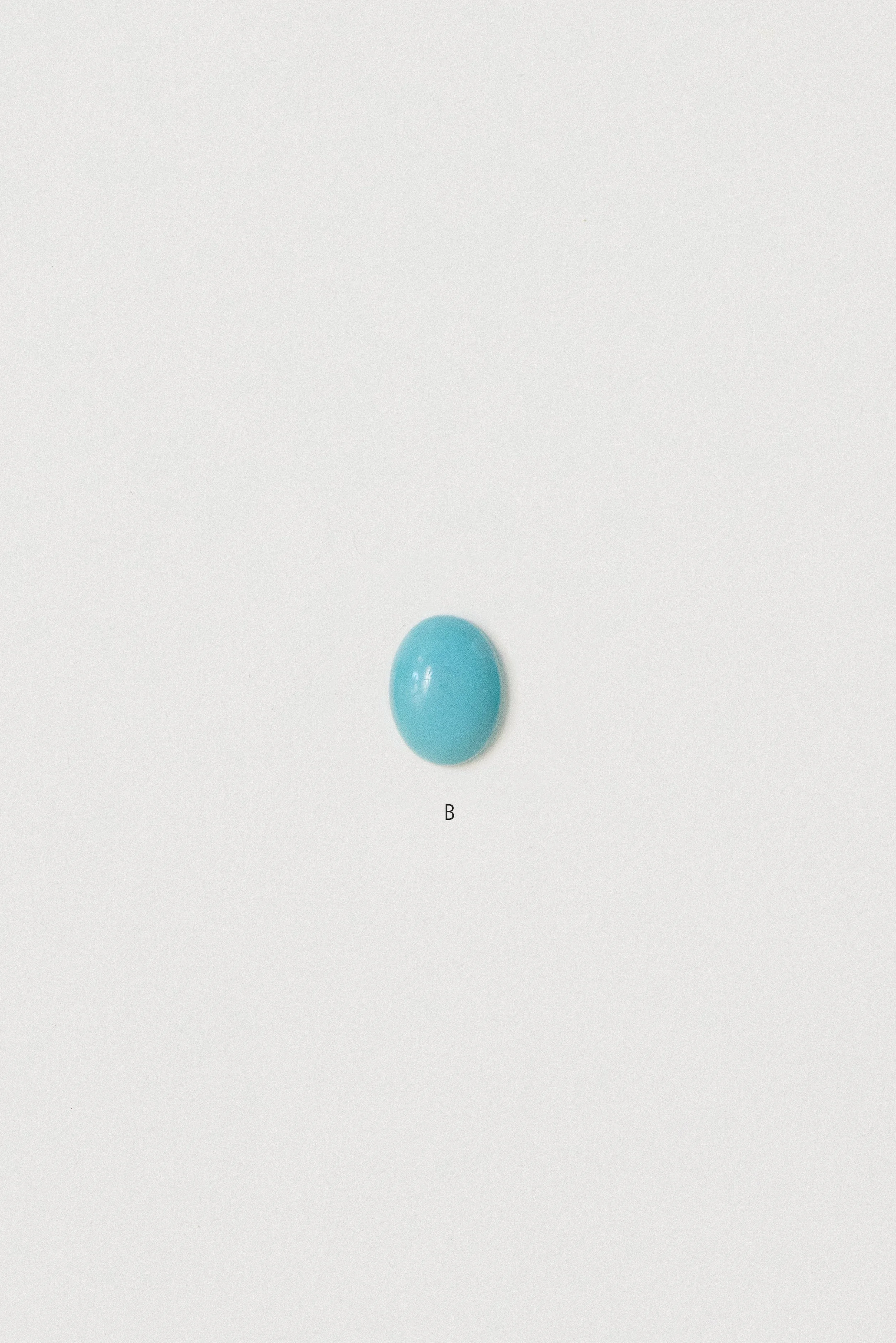 Natural turquoise cabochon from Sinai, Egypt labeled B on a white background.