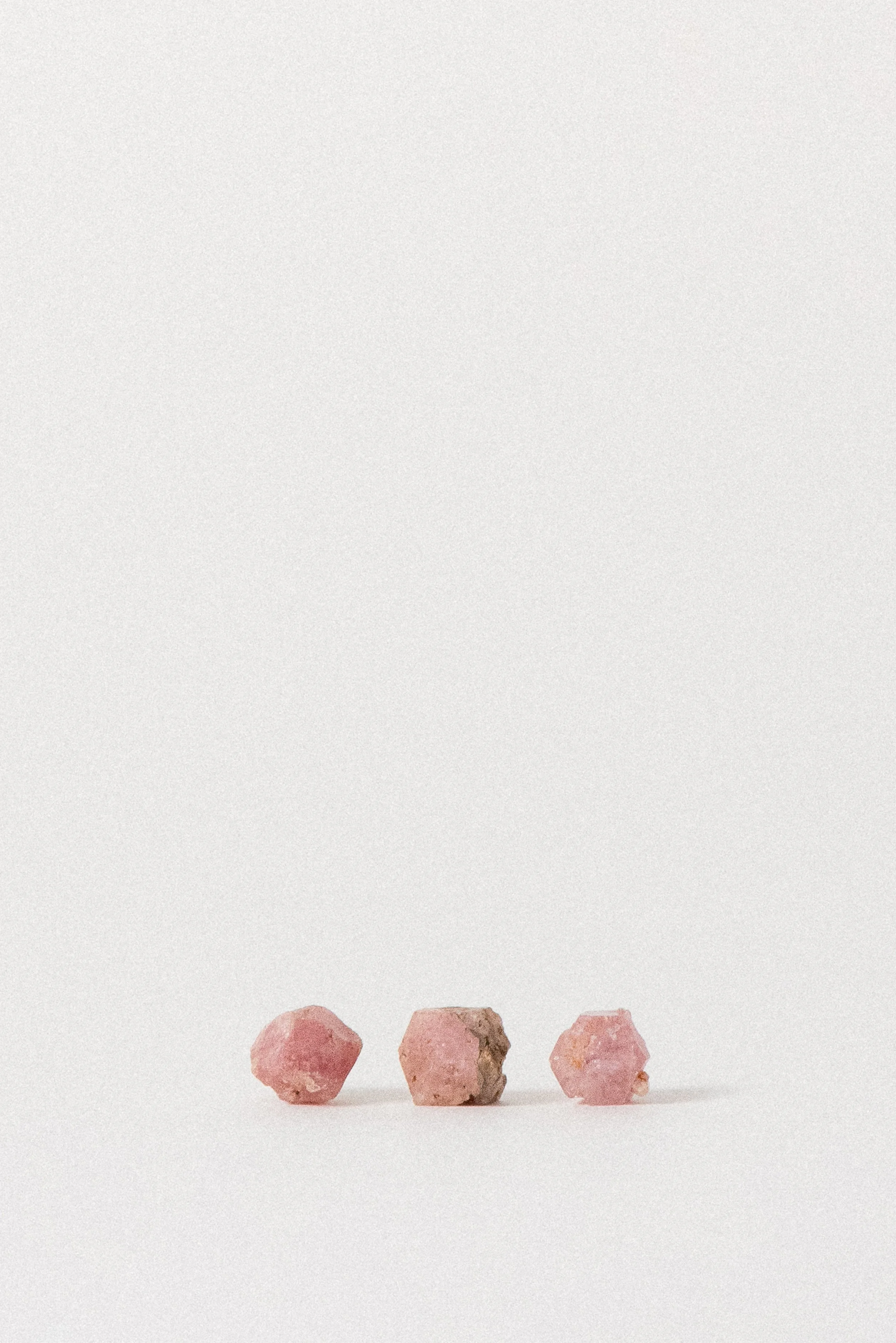 Row of small natural pink garnet crystals from Xalostoc, Mexico displayed on white background