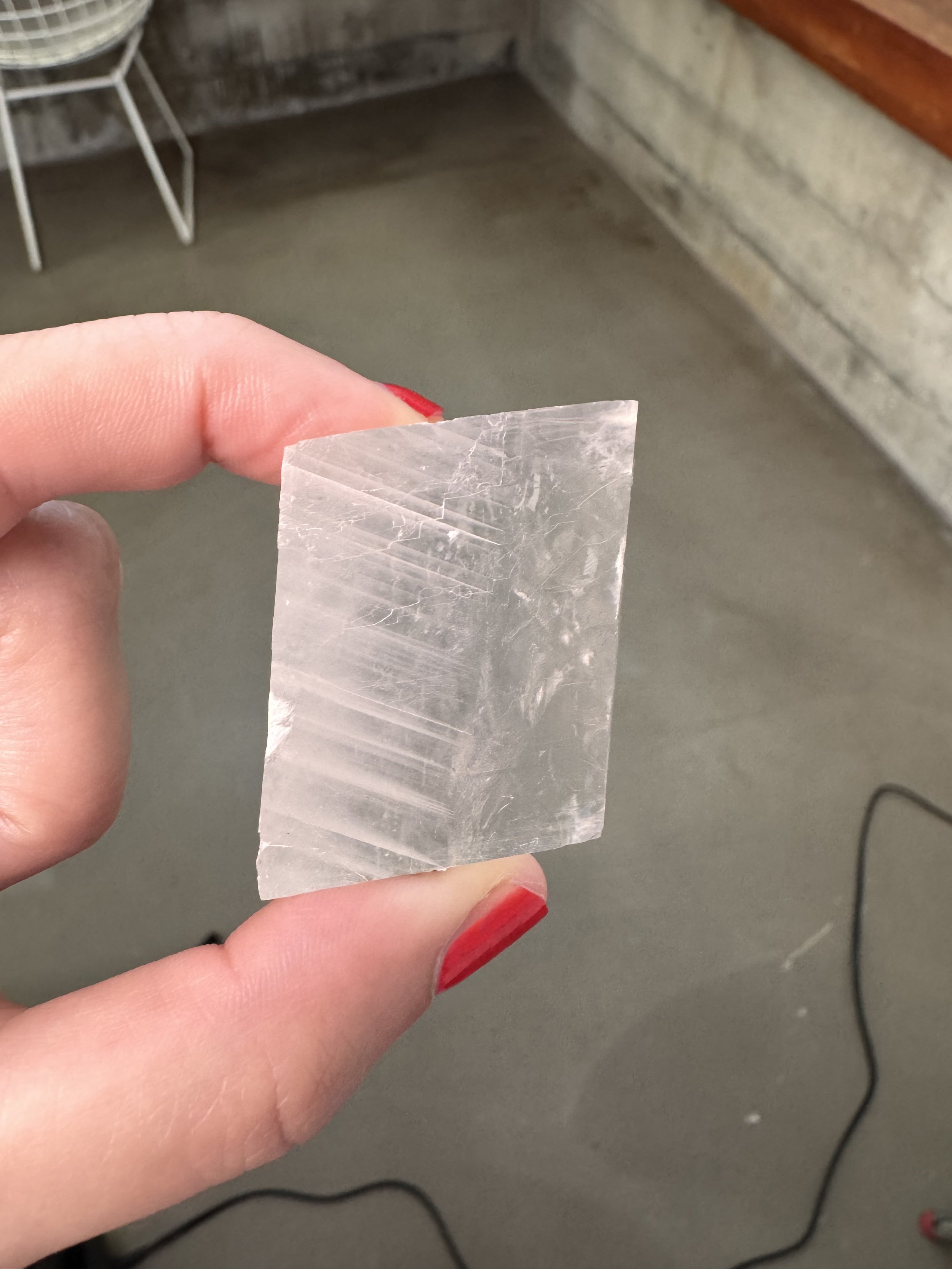 Clear optical calcite crystal held in hand, showing rhombohedral structure and internal striations. Ethically sourced from Mexico.