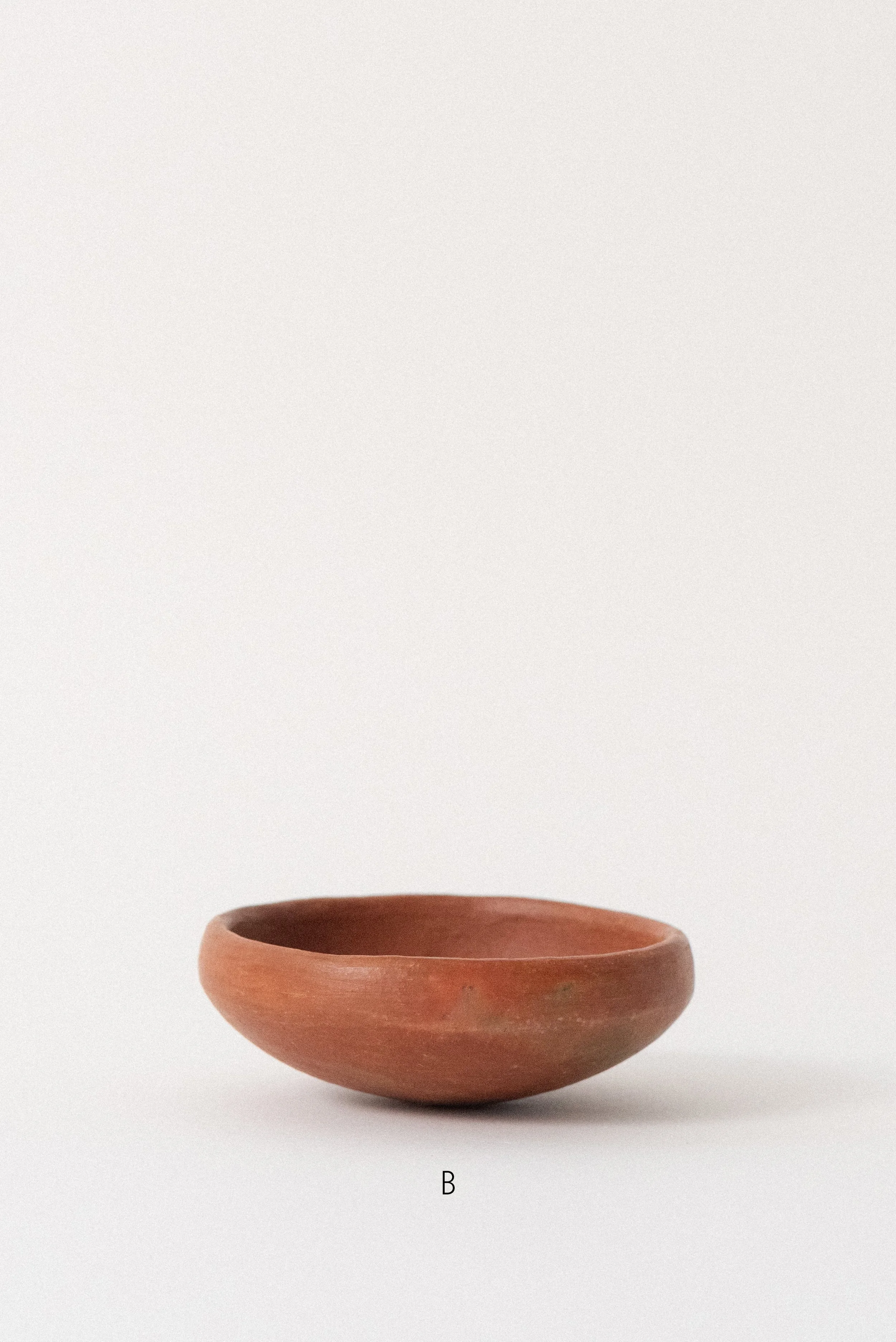 Single handmade barro rojo red clay bowl labeled B, crafted in Oaxaca, Mexico, displayed against a white background — rustic and versatile kitchenware.