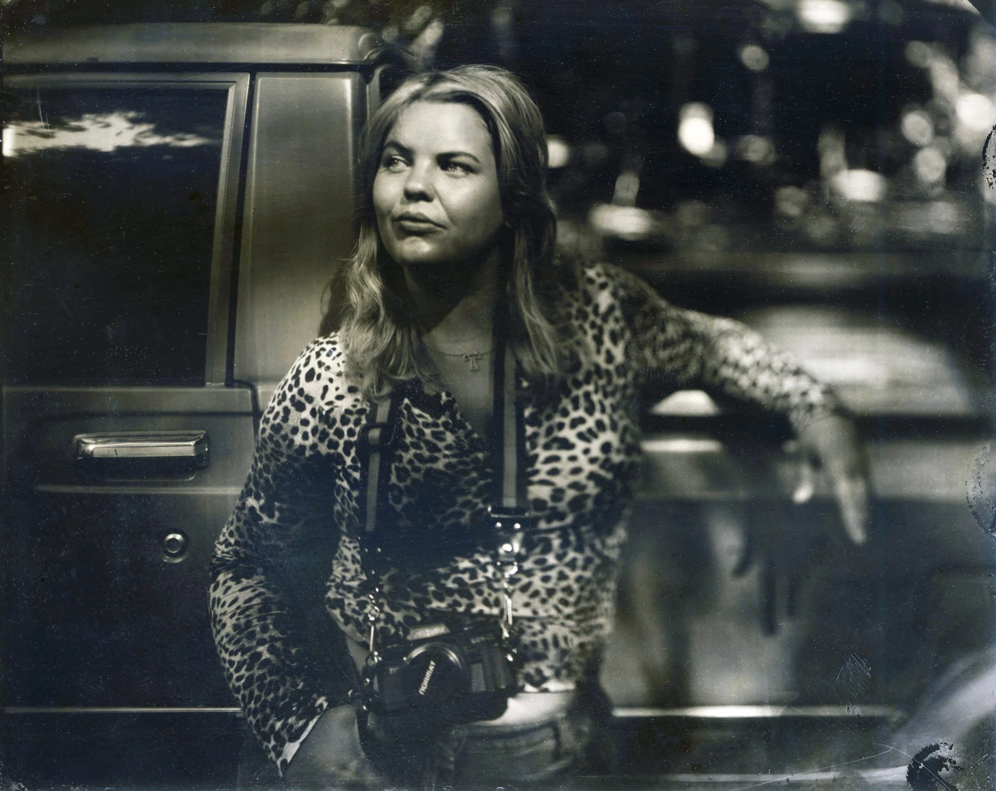 Tin type portrait of a woman  with a camera around her neck leaning against an old tacoma truck.  The photograph was made with the historic wet collodion photography process.
