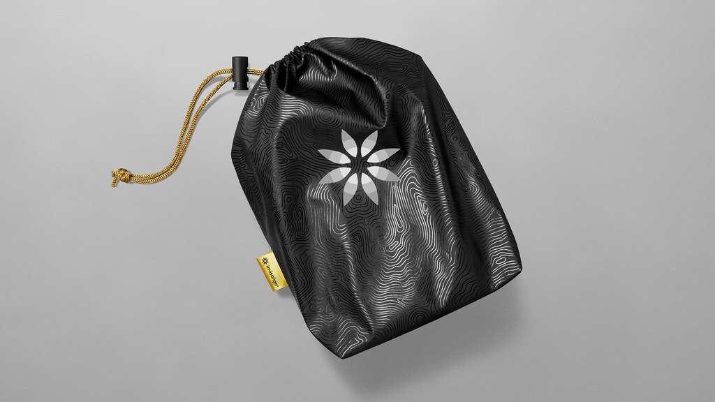 A black drawstring bag with a white floral design, a yellow tag, and a yellow cord closure, placed on a gray background.