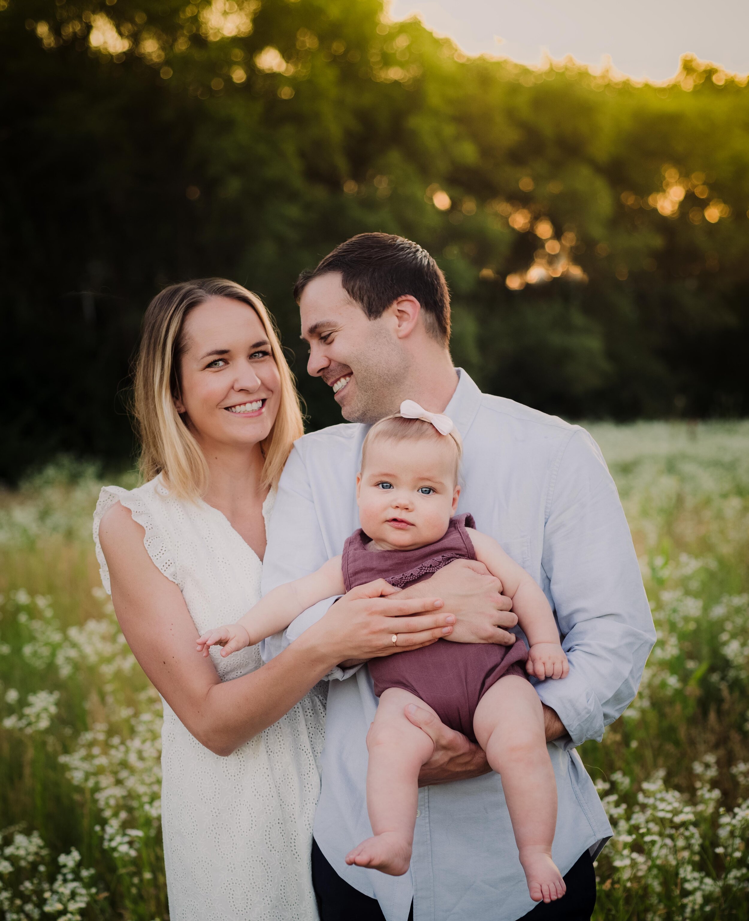 Family outfit ideas for your family pictures. Mom in a white lace dress, baby in a purple romper from Bloom Kids Collection and dad in a light blue button down shirt with sleeves rolled in West Lafayette, Indiana with Kelly McPhail Photography.