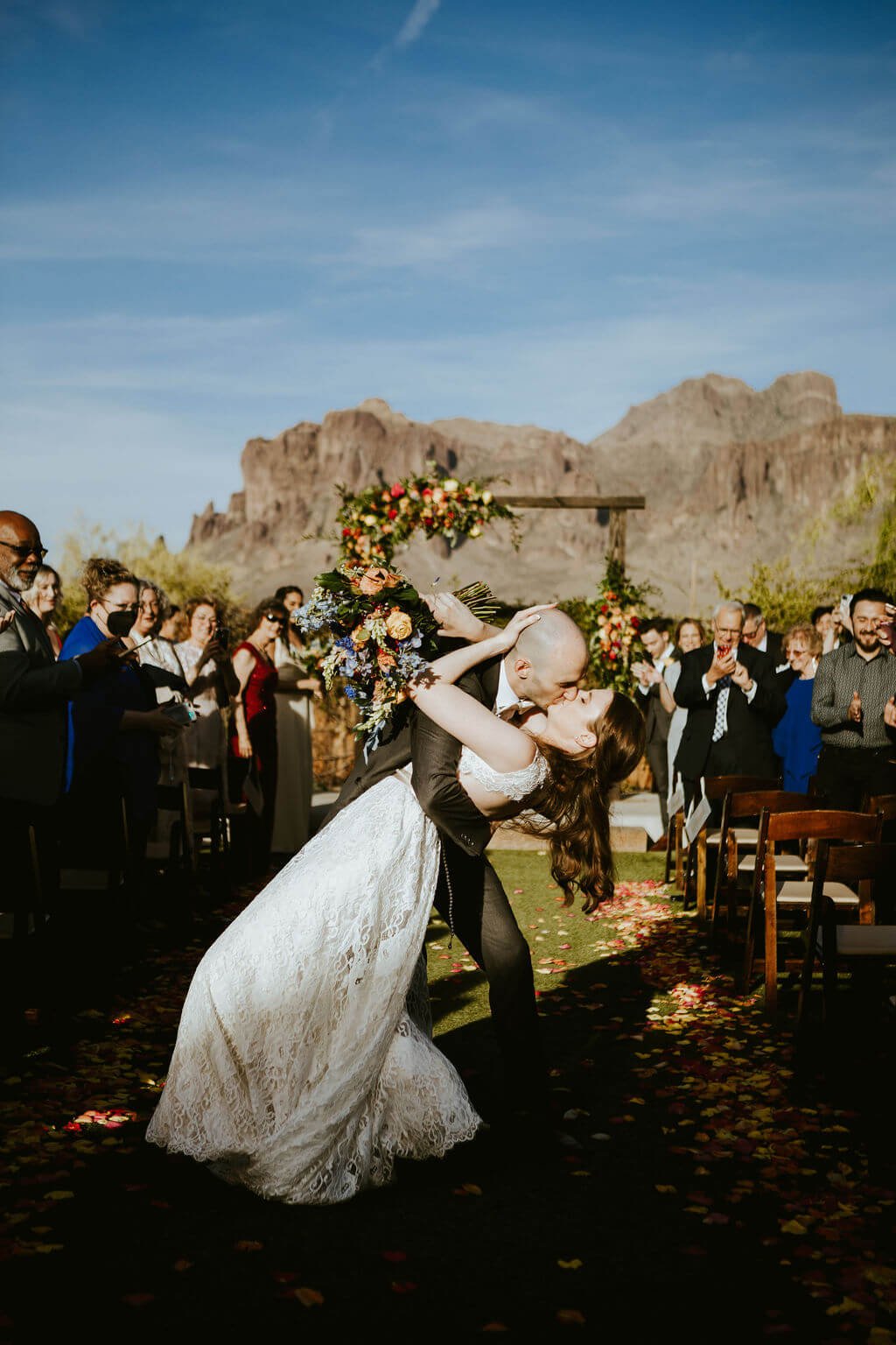 Bride and groom kissing at the end of wedding aisle at Arizona desert wedding