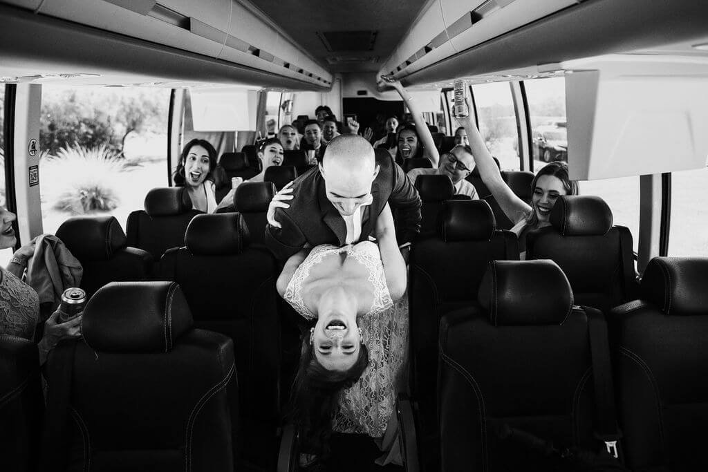 Bride and groom dance on party bus with bridal party