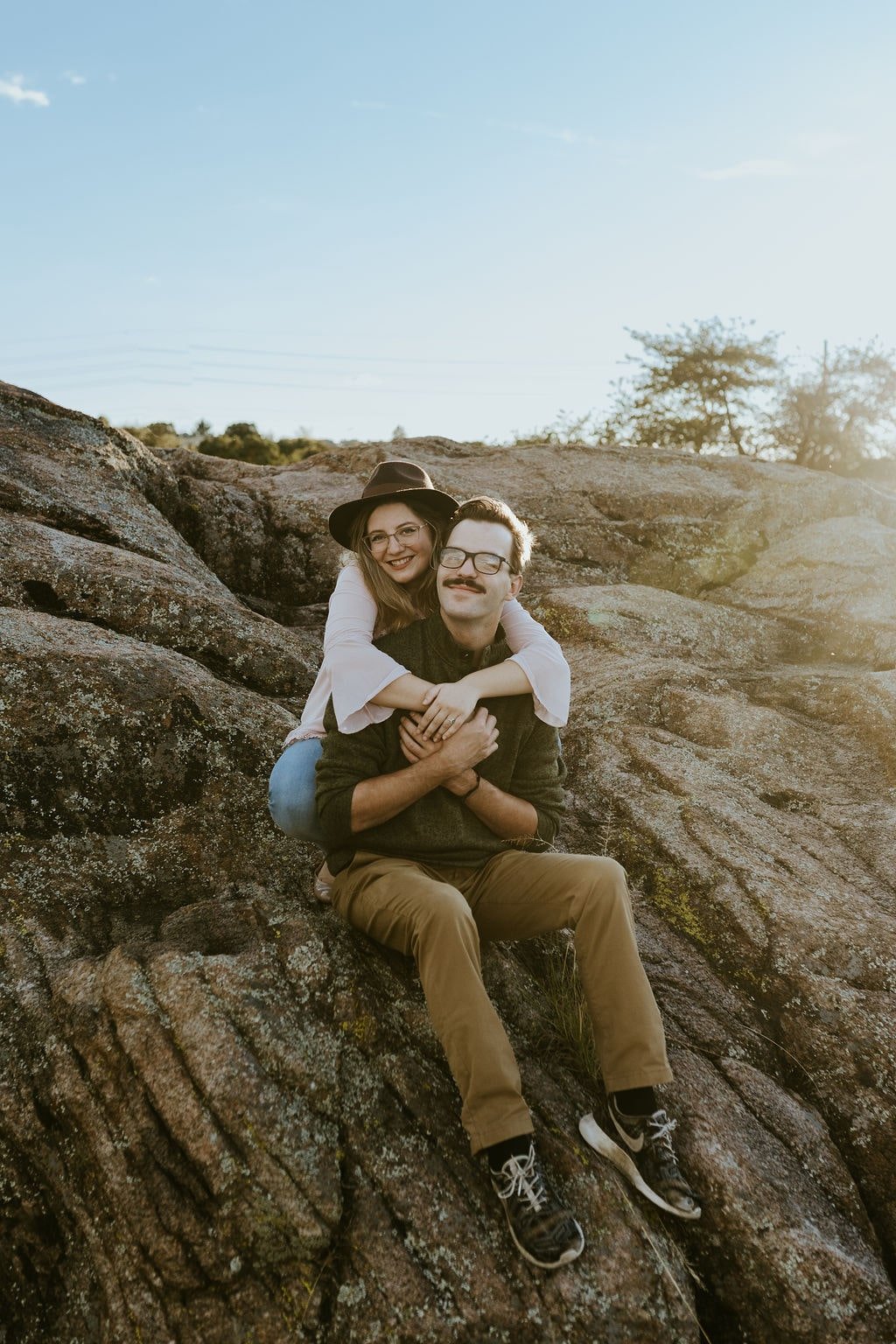 Couple sitting on a desert rock during Arizona engagement photos